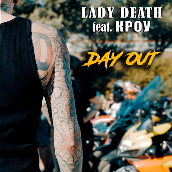 Part of a person's arm with multiple tattoos, wearing a black sleeveless shirt, with a background of parked motorcycles and a sunny outdoor setting