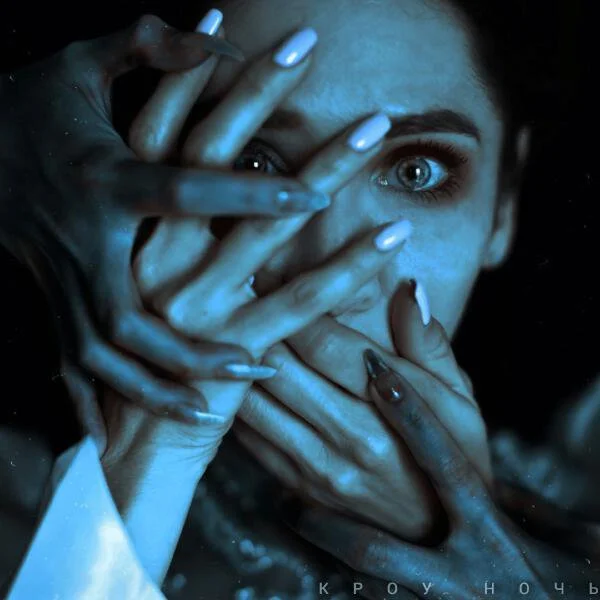 Close-up of a woman with blue eyes, partially covering her face with multiple hands, some with painted nails, in a dramatic and intense scene with dark background.