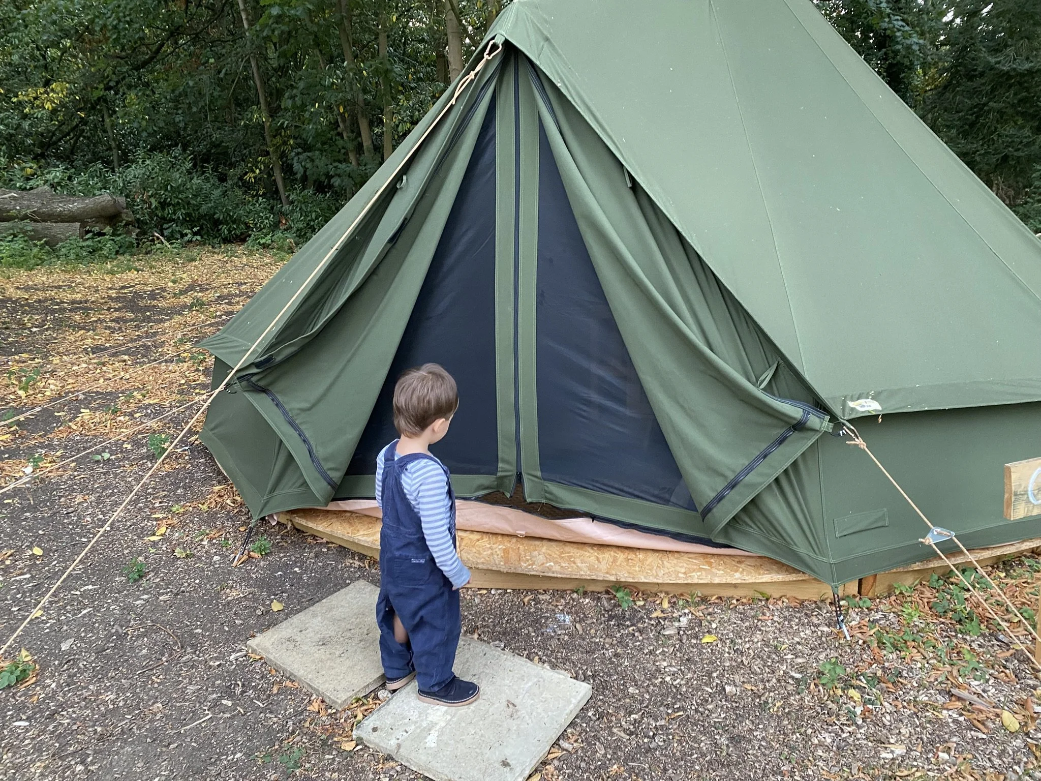 Child exploring bell tent entrance at family-friendly glamping site
