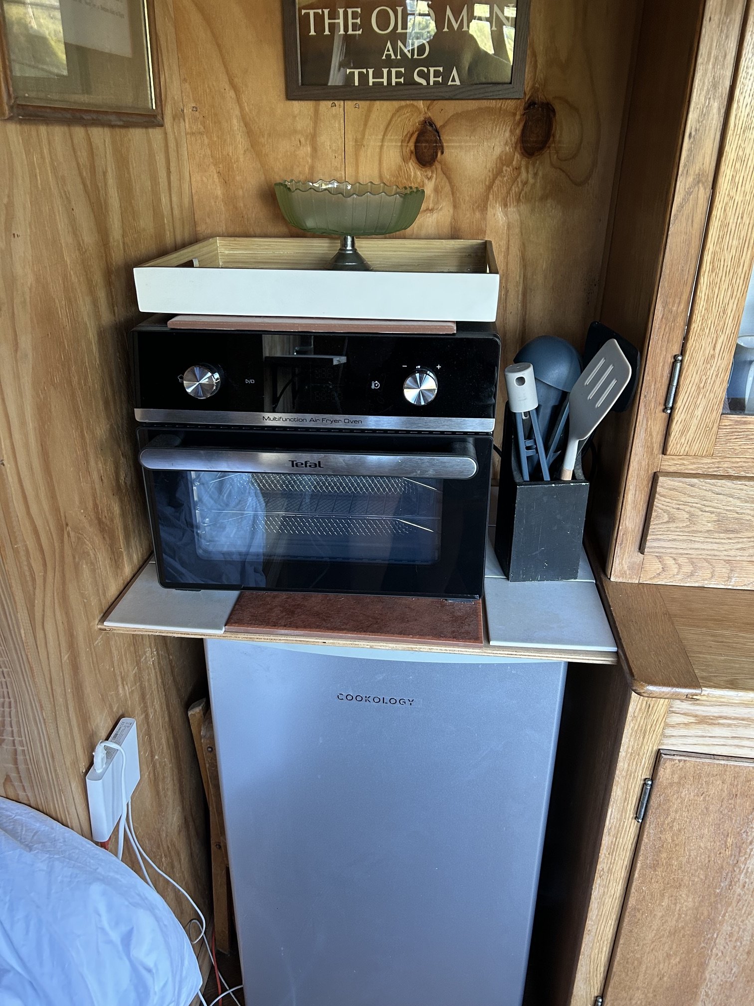 Compact kitchen with air fryer oven and fridge inside shepherd's wagon
