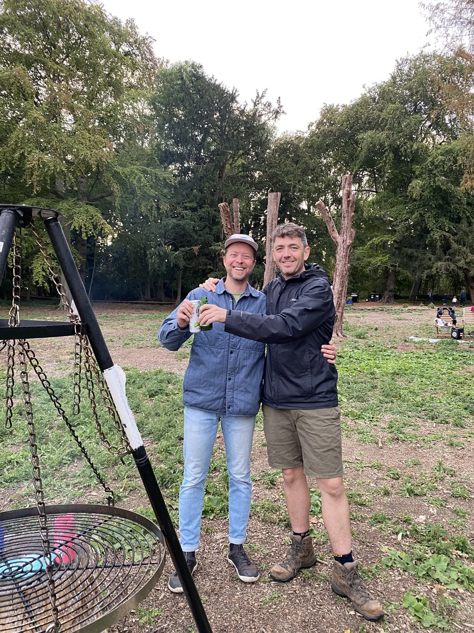 Guests by fire pit grill at off-grid glamping site