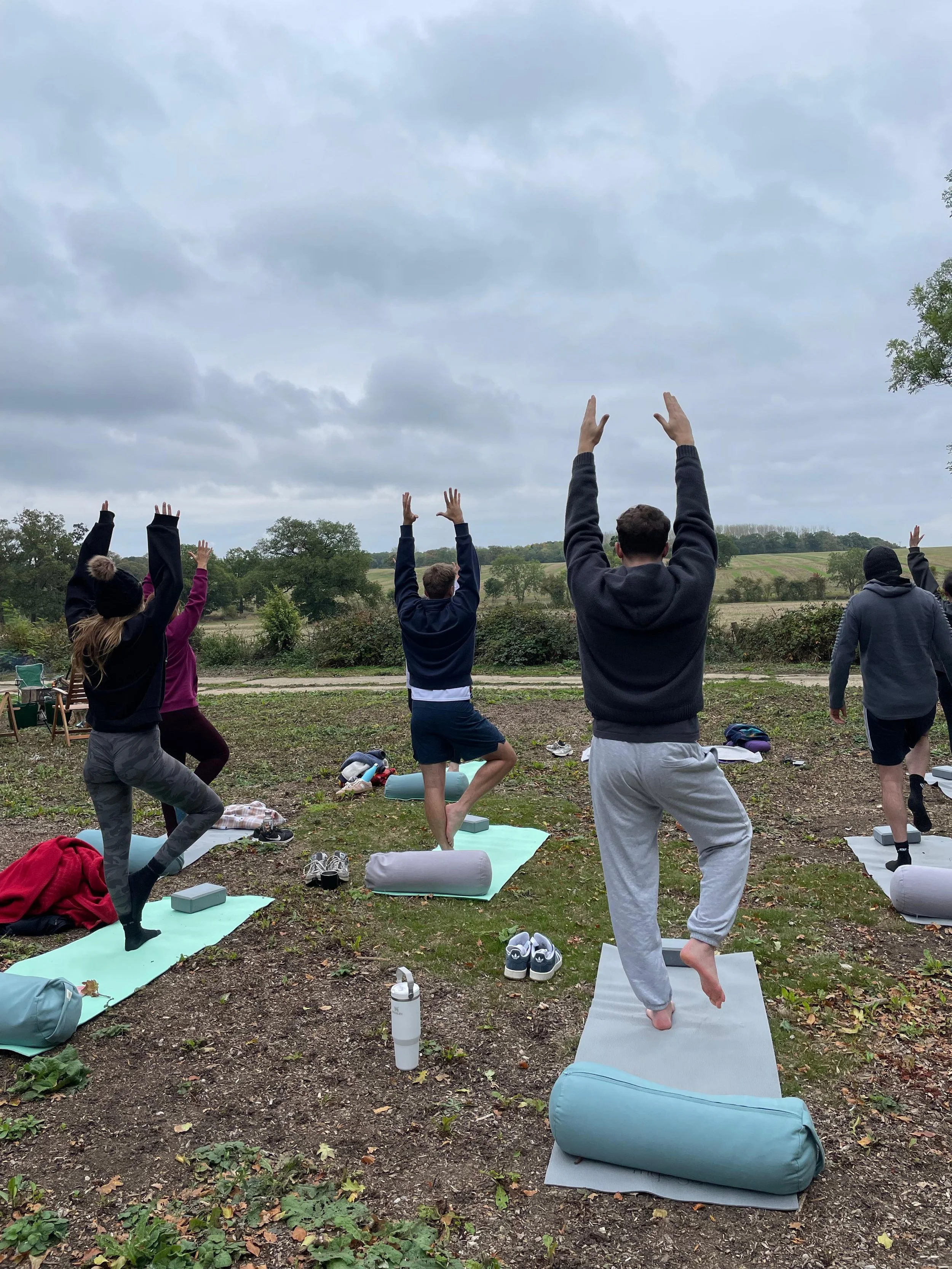 Guests practising yoga outdoors with open countryside views