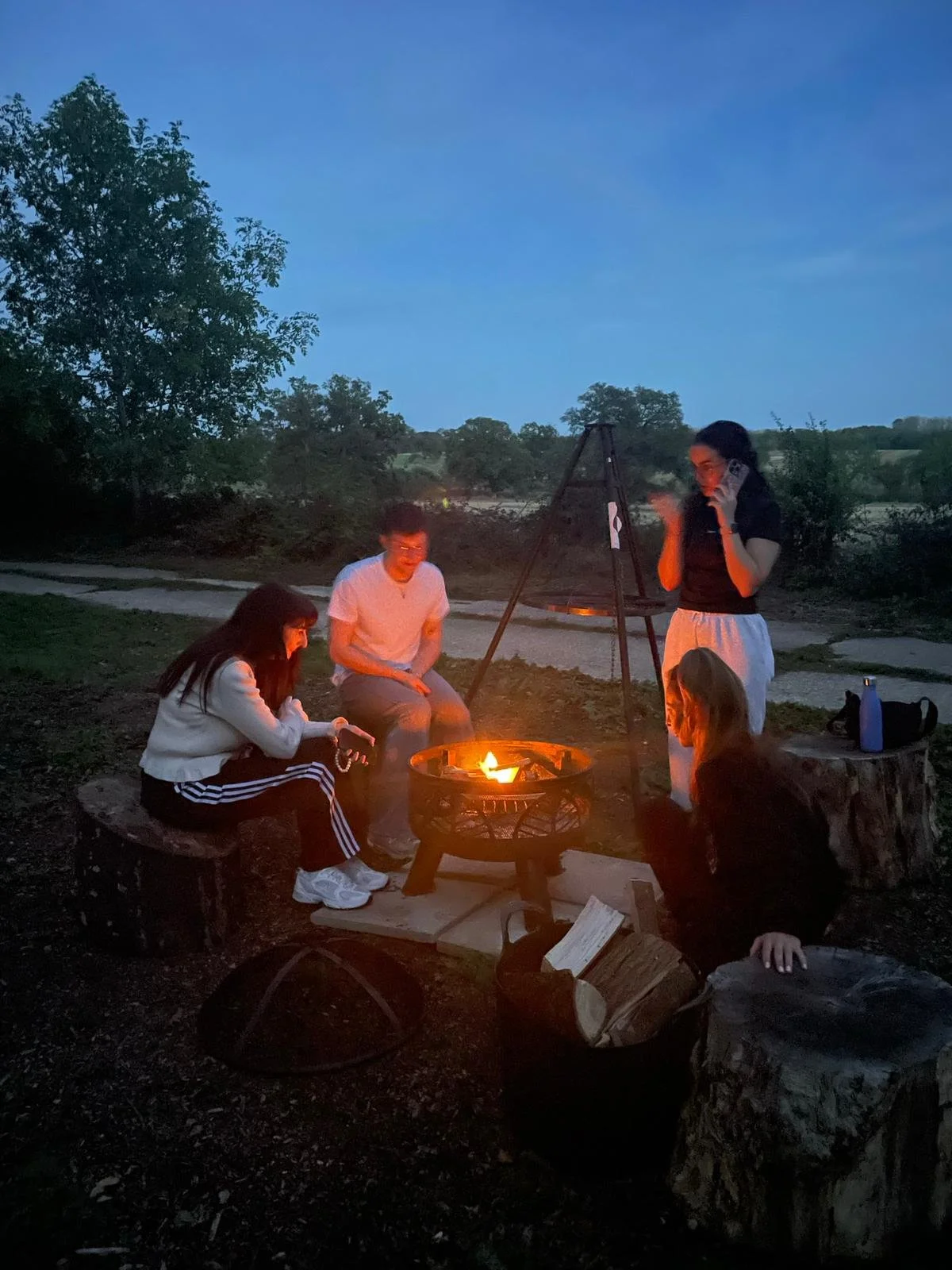Guests gathered around a fire pit at dusk during a private event