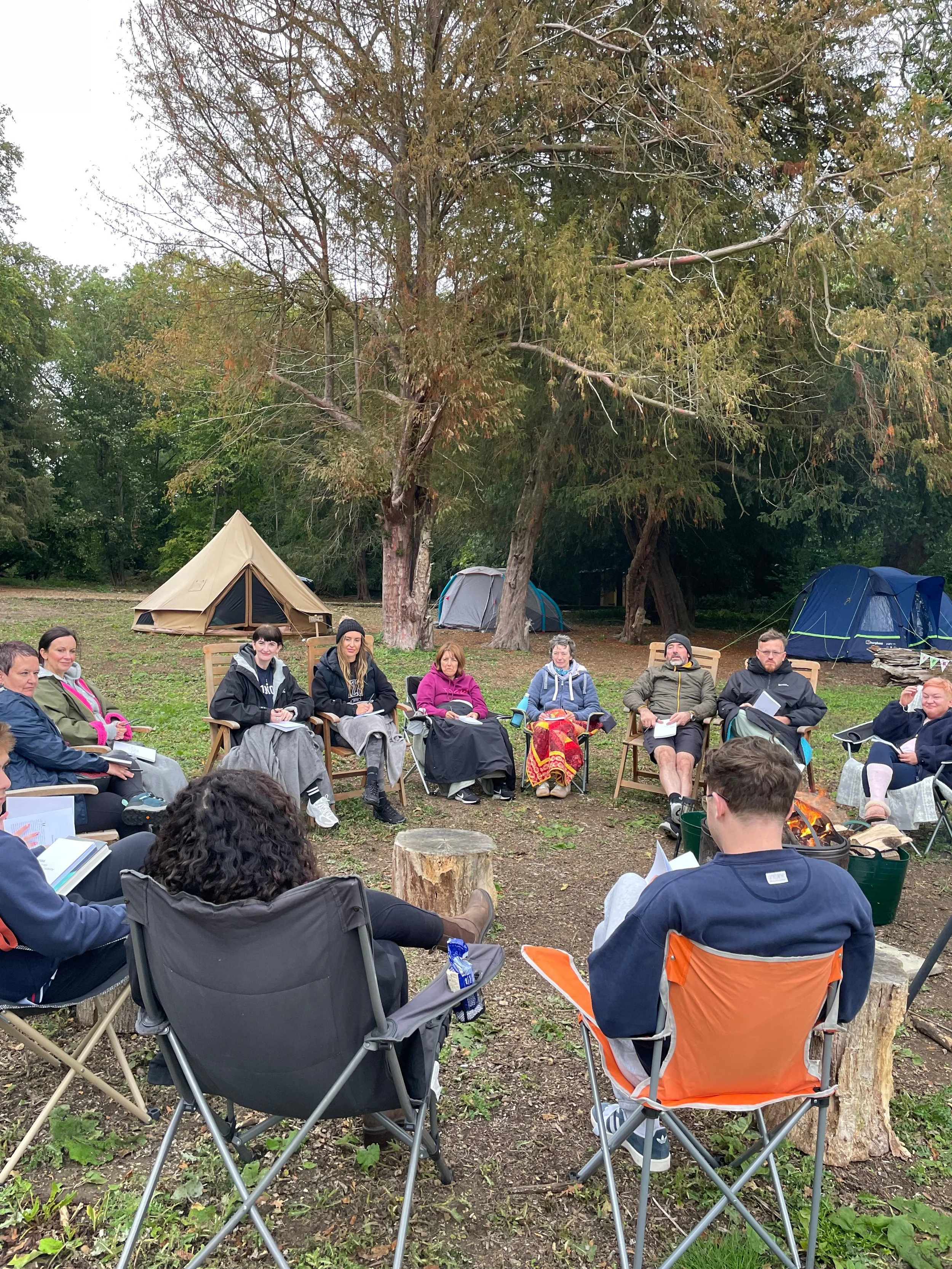 Retreat group gathered around the fire pit at woodland glamping site