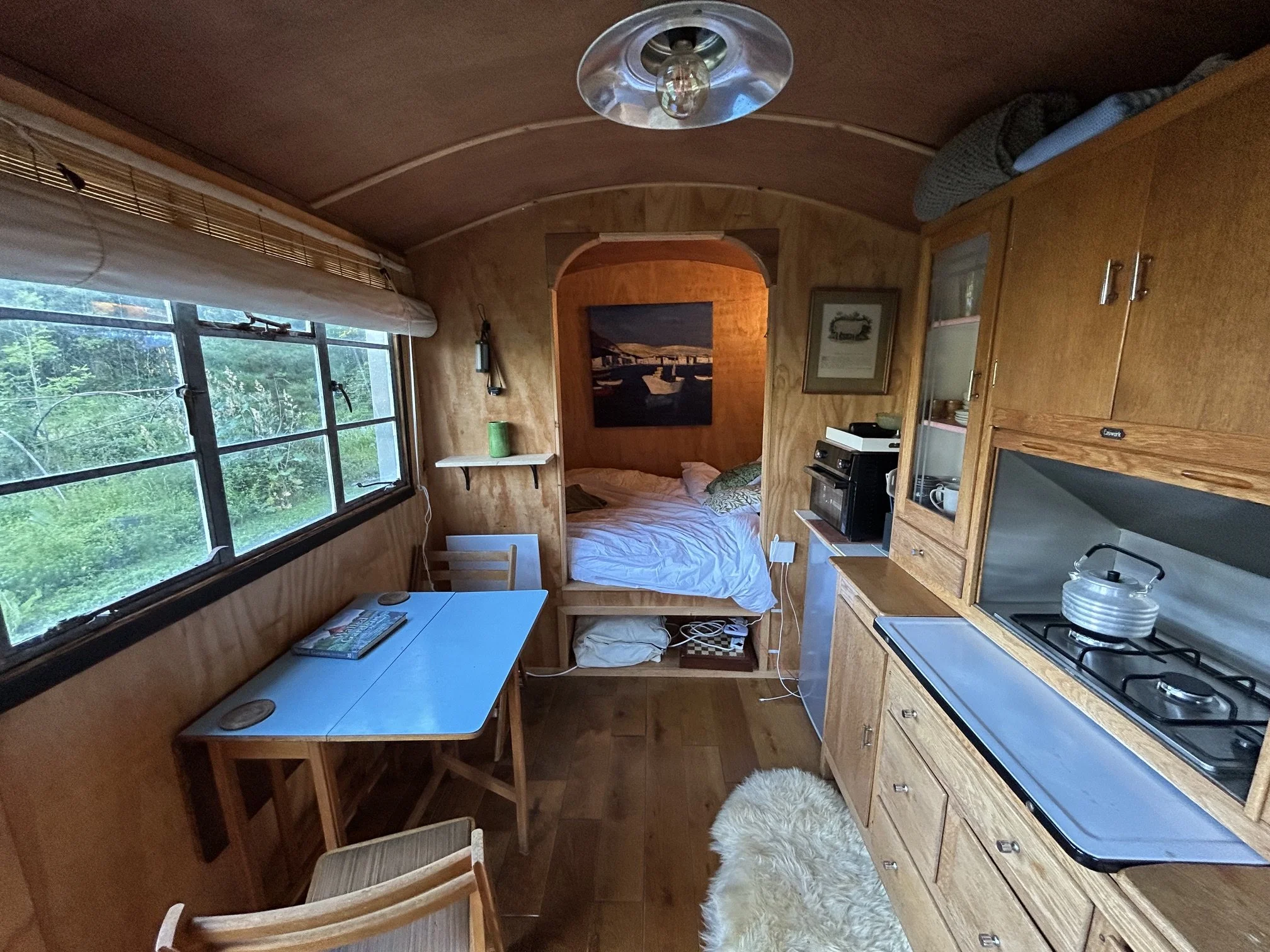 Shepherd's wagon living space with dining table, bed nook and oak dresser
