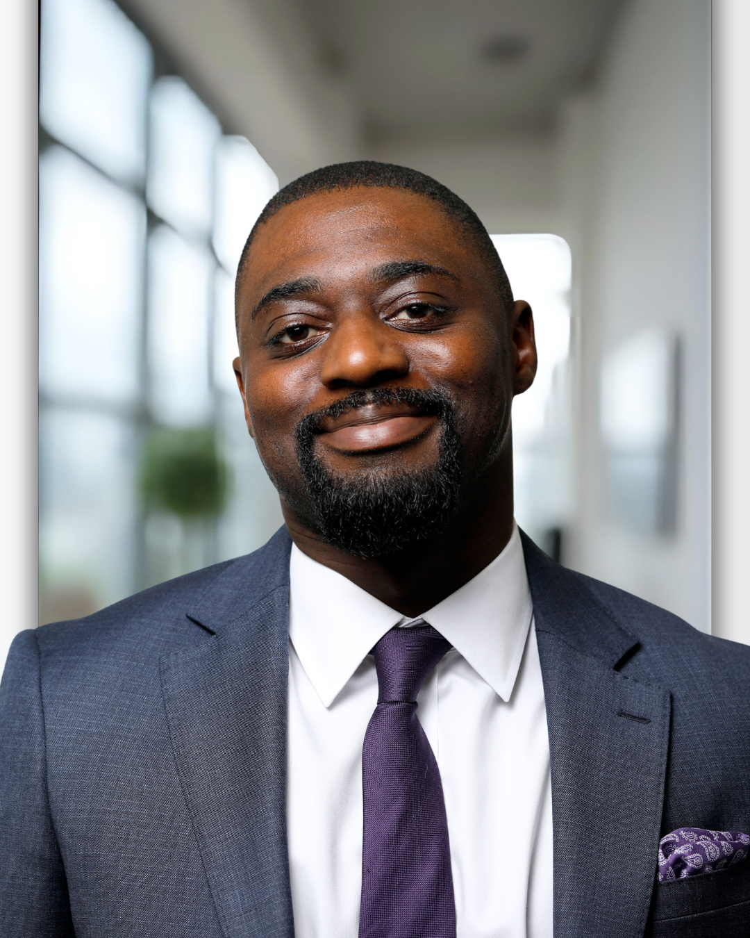 Portrait of a smiling Black man in a business suit and tie in an office setting.