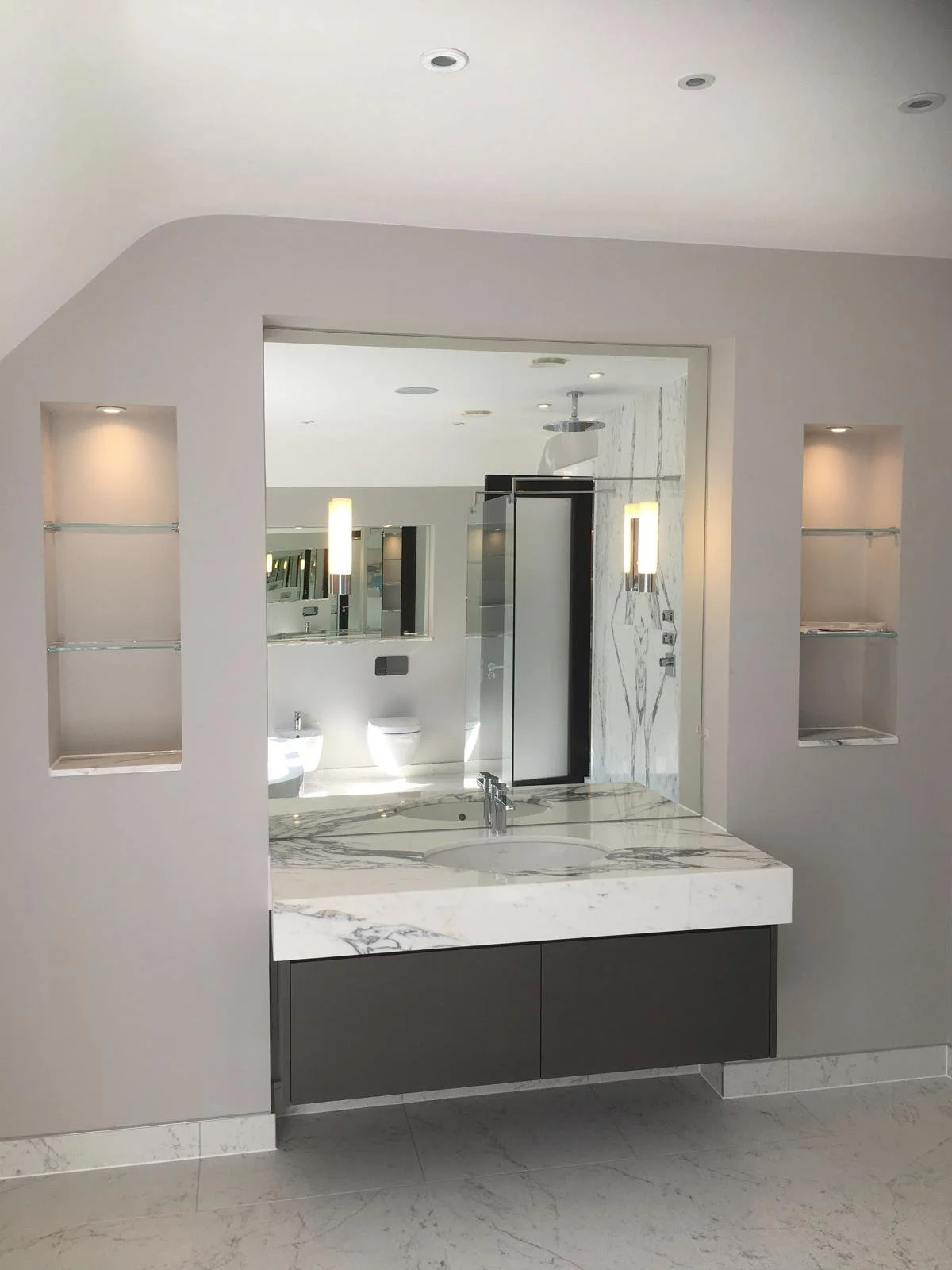 Large fitted mirror above double vanity unit with built-in shelving in a contemporary bathroom renovation.