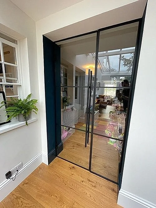 Crittall-style glass door room divider formed from slim black-framed toughened glass panels