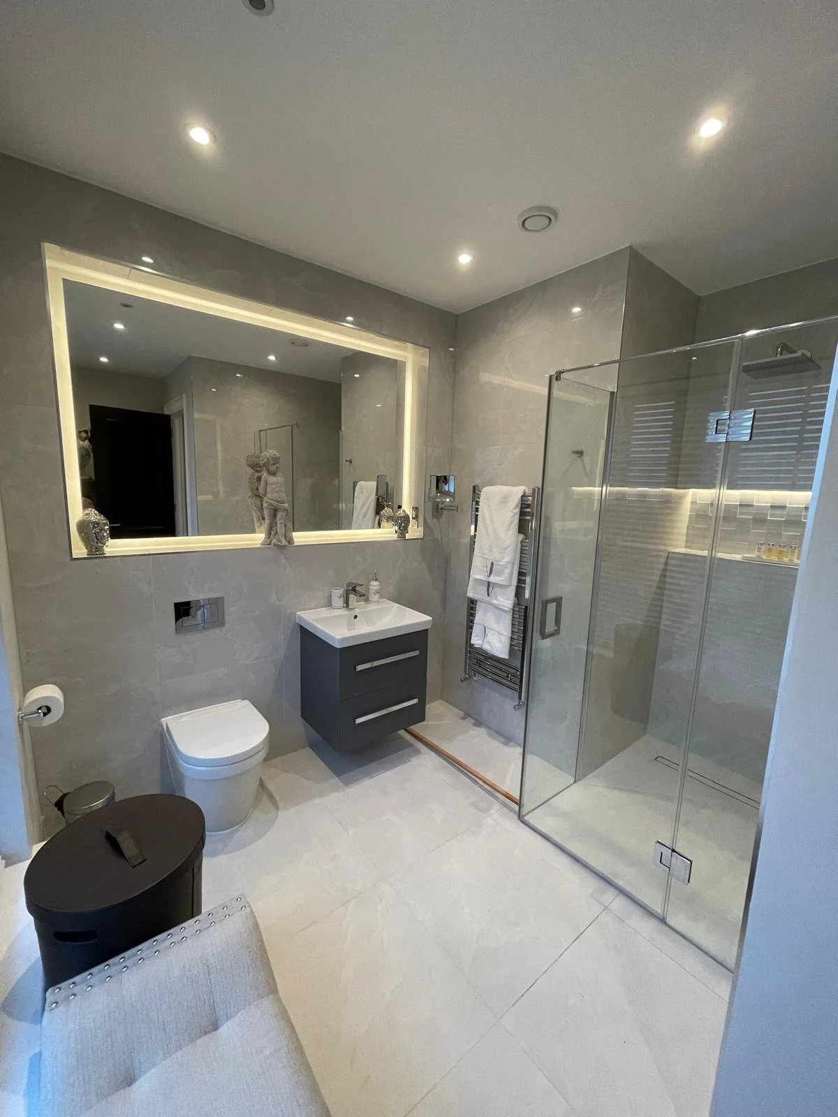 Large LED illuminated mirror fitted above a vanity basin providing soft ambient lighting in a modern bathroom design.