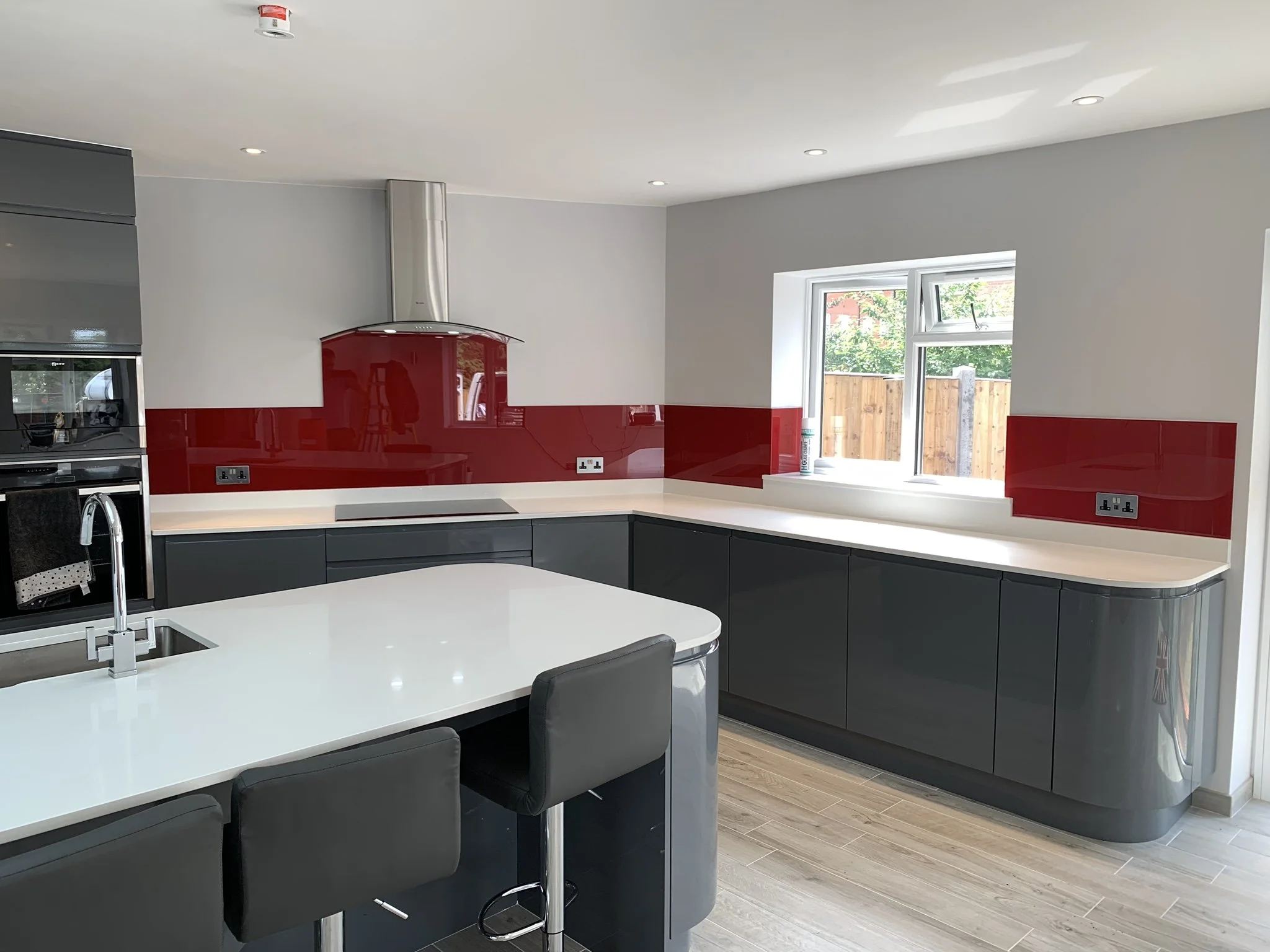 red glass splashback behind hob in modern kitchen London.JPEG