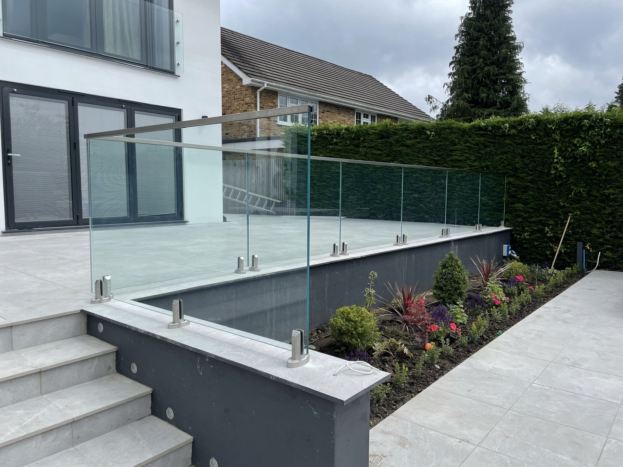 Spigot-fixed toughened laminated glass balustrade on raised patio with stainless steel spigots