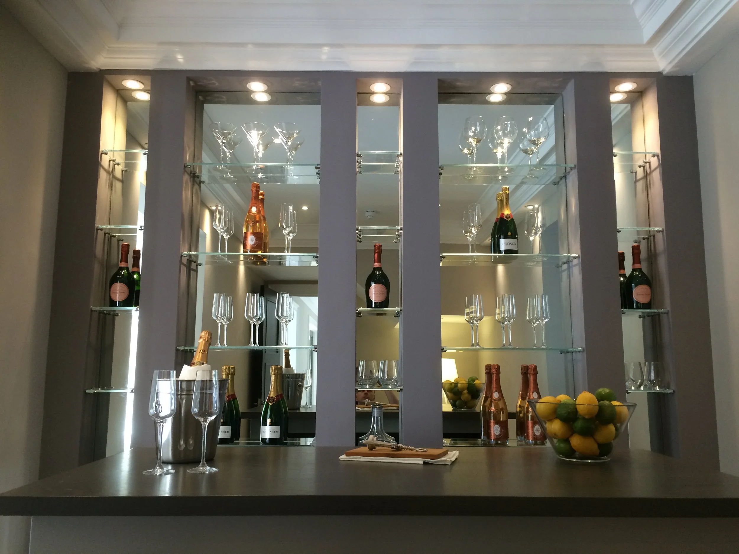 Luxury mirrored drinks display cabinet with glass shelves designed for champagne and glassware storage in a high-end interior bar area.