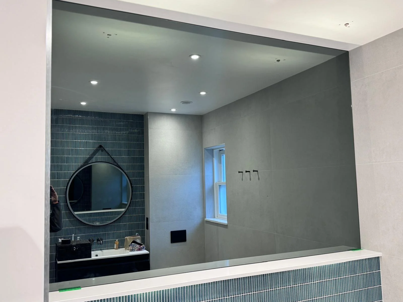 Grey tinted decorative mirror installed as a wall feature providing a stylish reflective surface in a contemporary interior.