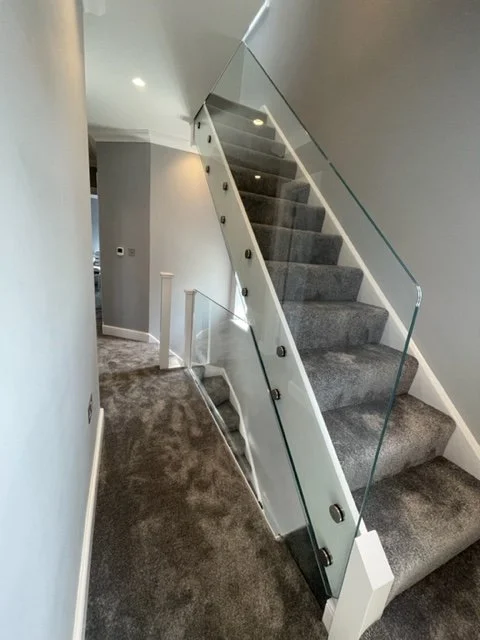 Glass staircase balustrade installation in Surrey with frameless toughened laminated panels