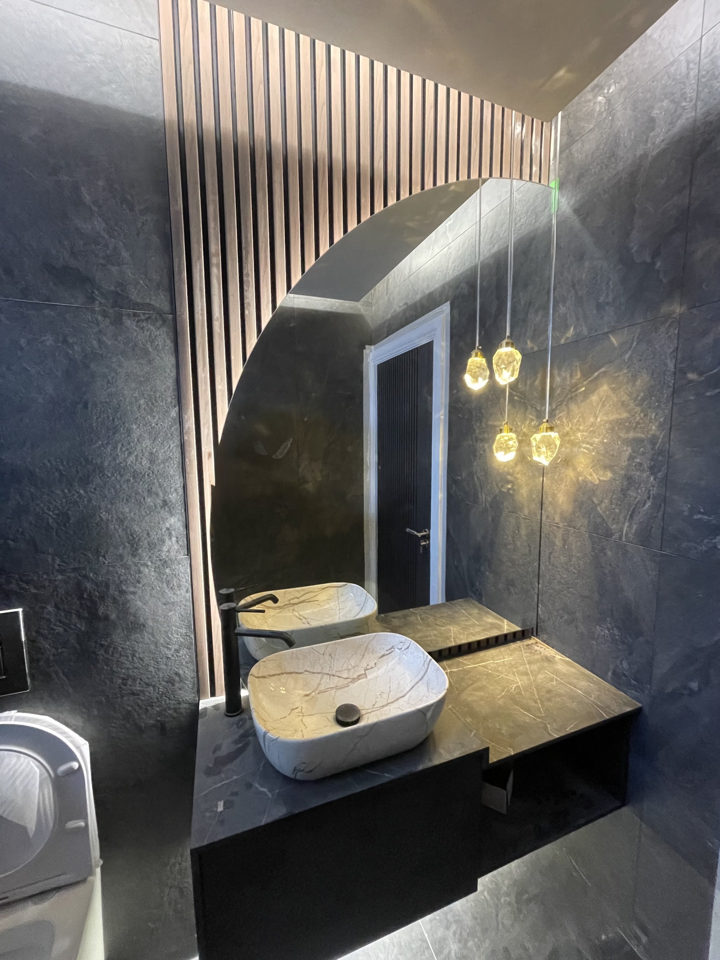 Bespoke shaped LED illuminated mirror fitted above a bathroom basin providing stylish lighting and a luxury finish.