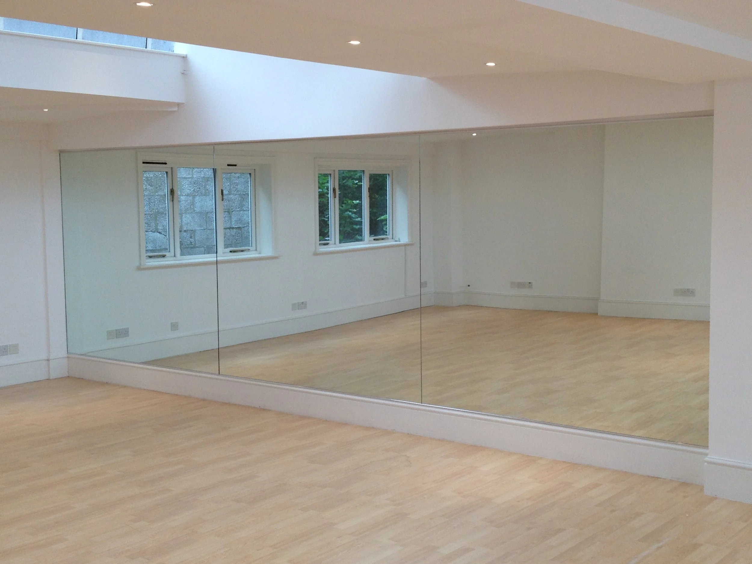 Full height fitness studio mirror installation creating a large reflective workout space for spinning classes and gym training sessions.