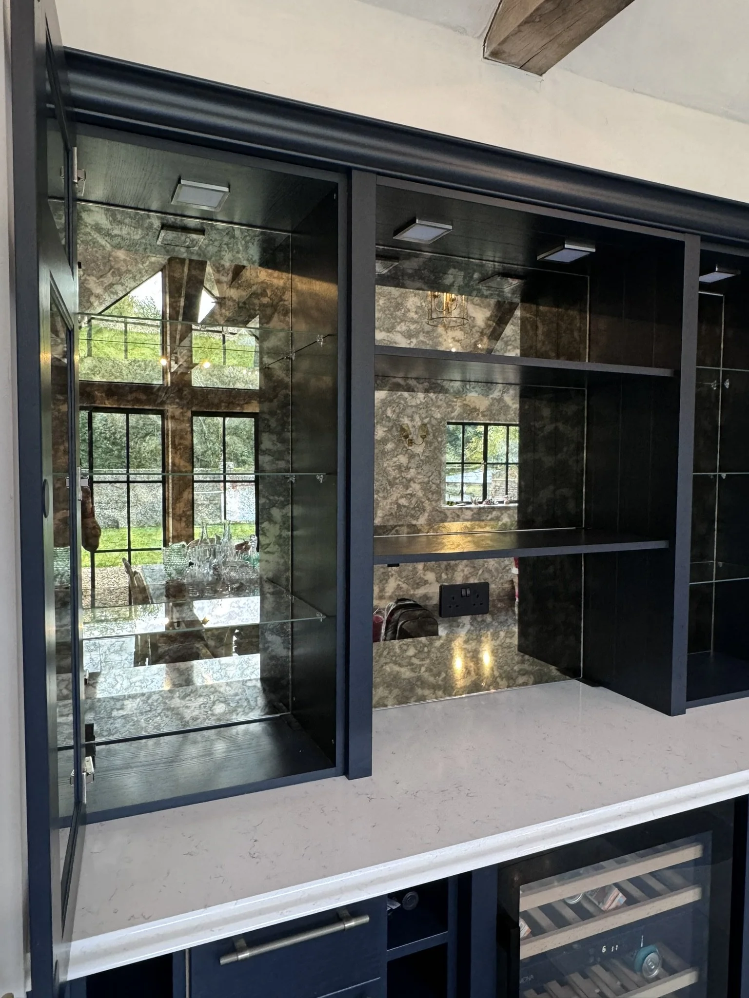 Antique distressed gold and bronze mirror panels with glass shelves, fitted to custom cupboards in Petersfield, East Hampshire with specialist mirror adhesive.