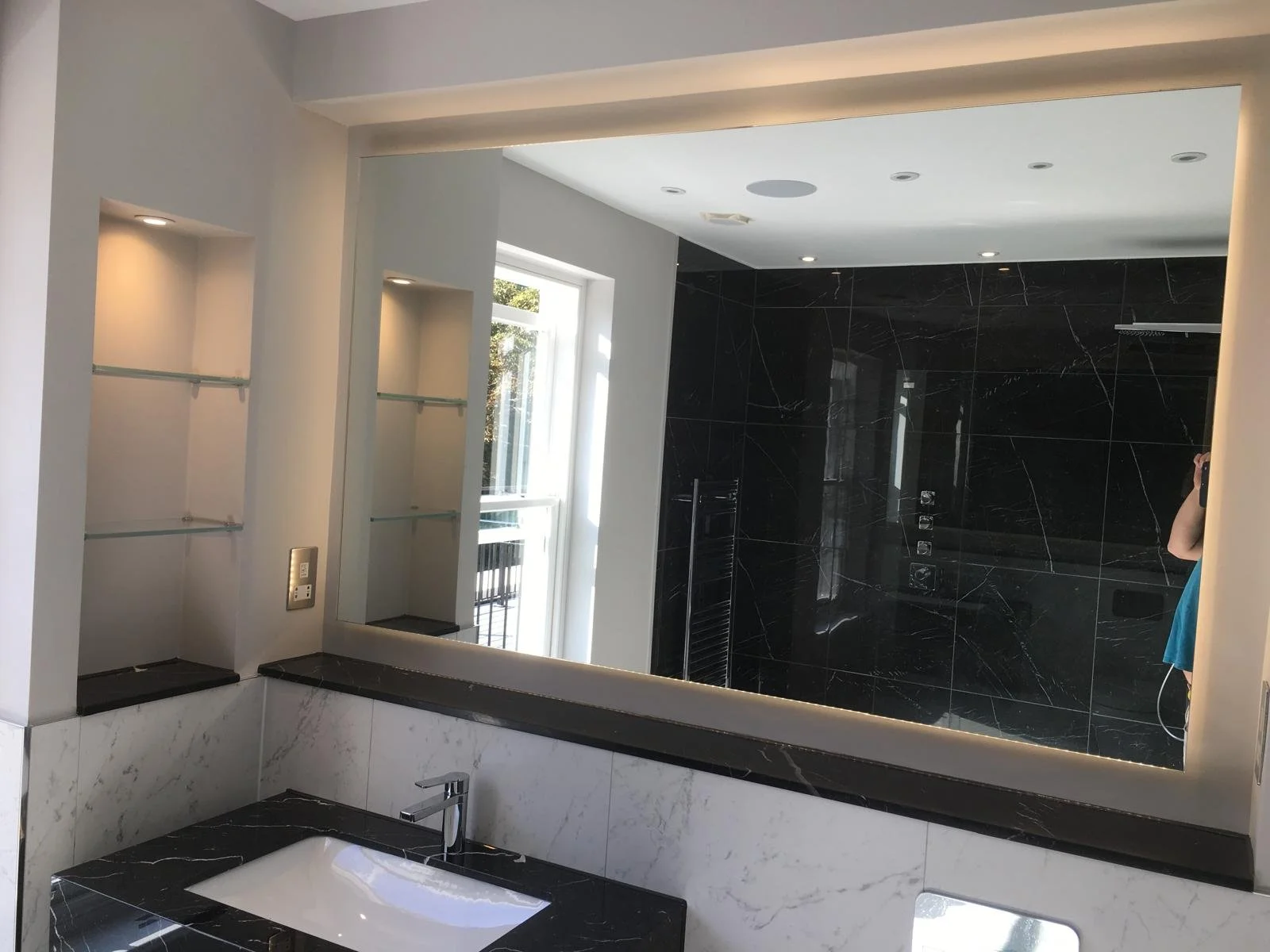 Bespoke bathroom mirror wall installed above a contemporary vanity basin with polished edges and precision fitting in a modern Surrey bathroom.