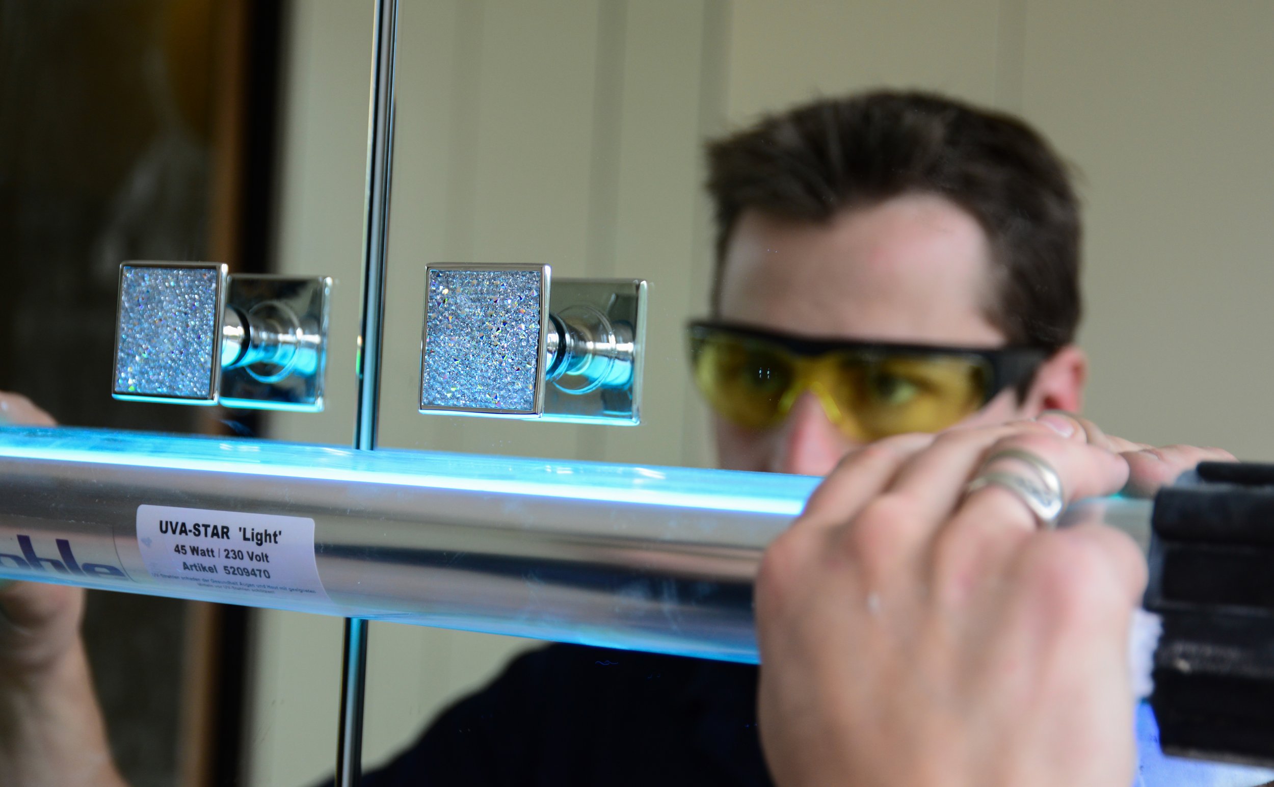 Glass to metal UV bonding process carried out by Hamilton Glass Products specialist.