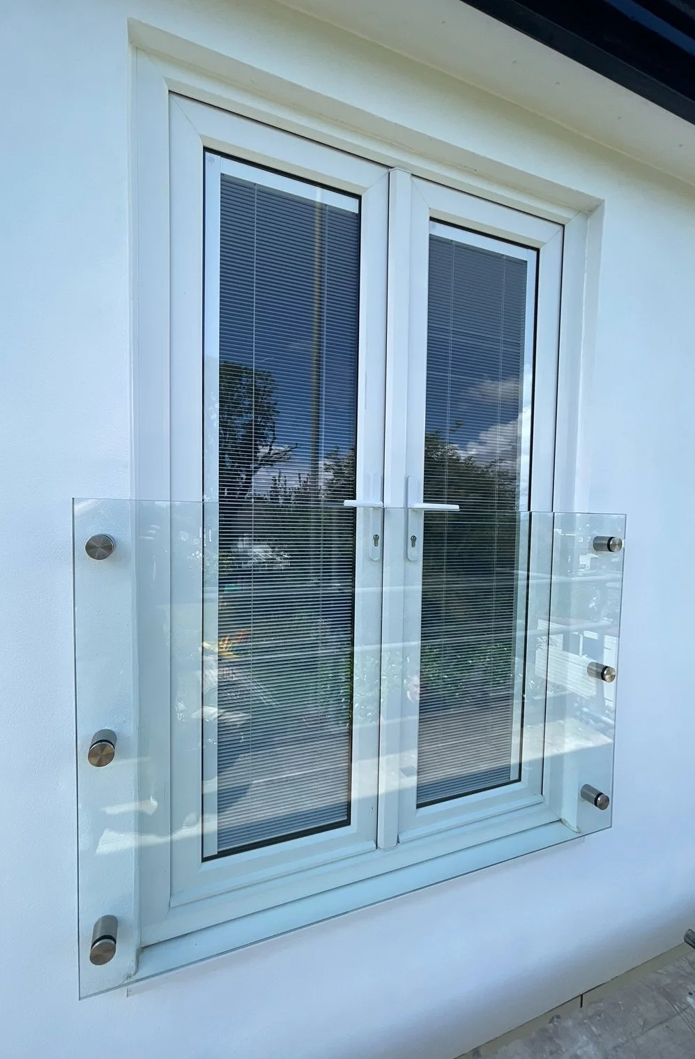 Toughened laminated glass Juliet balcony panel mounted on stainless steel standoff fixings for a floating appearance