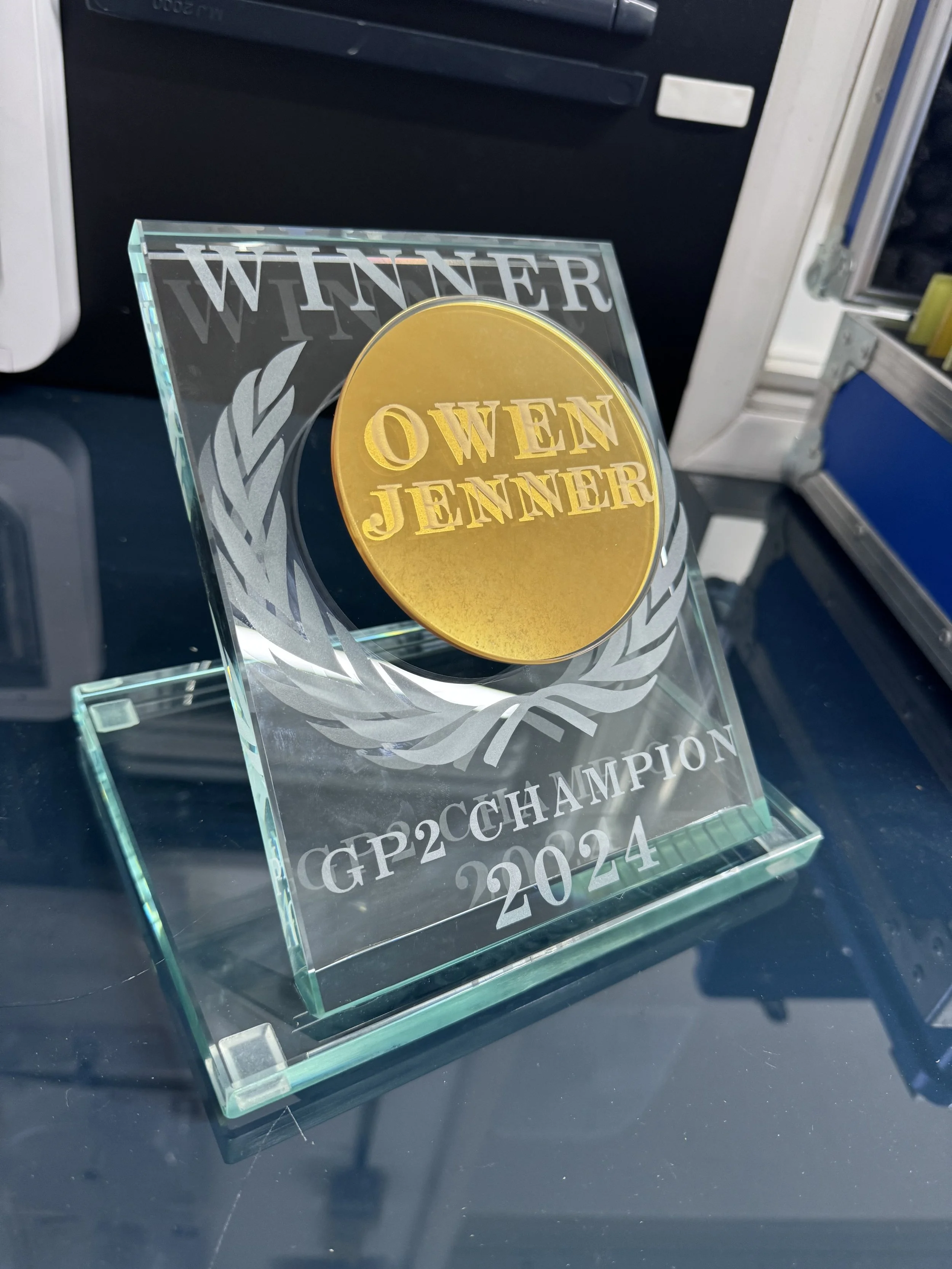 Custom glass trophy with etched detailing and a clear UV bonded base, designed for a corporate award ceremony. owen Jenner Bennets superbikes