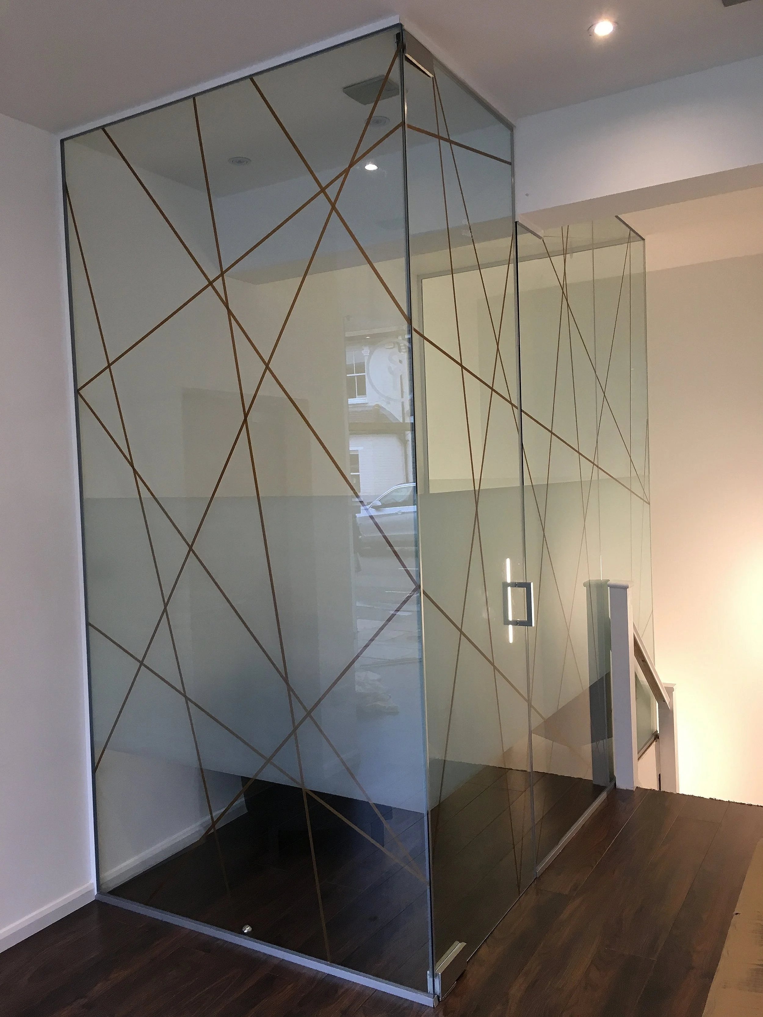 Frameless glass partition with decorative gold manifestation and frosted privacy section, cut to size and polished