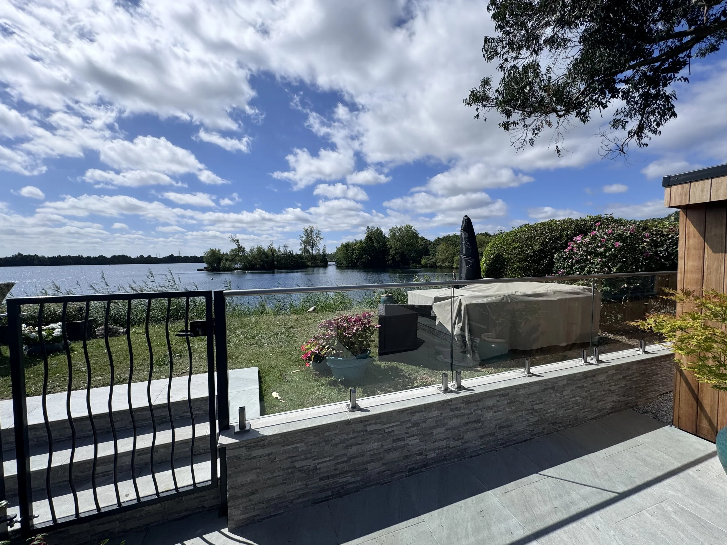 Clear toughened glass balustrade panels mounted on stainless steel spigots along a retaining wall edge
