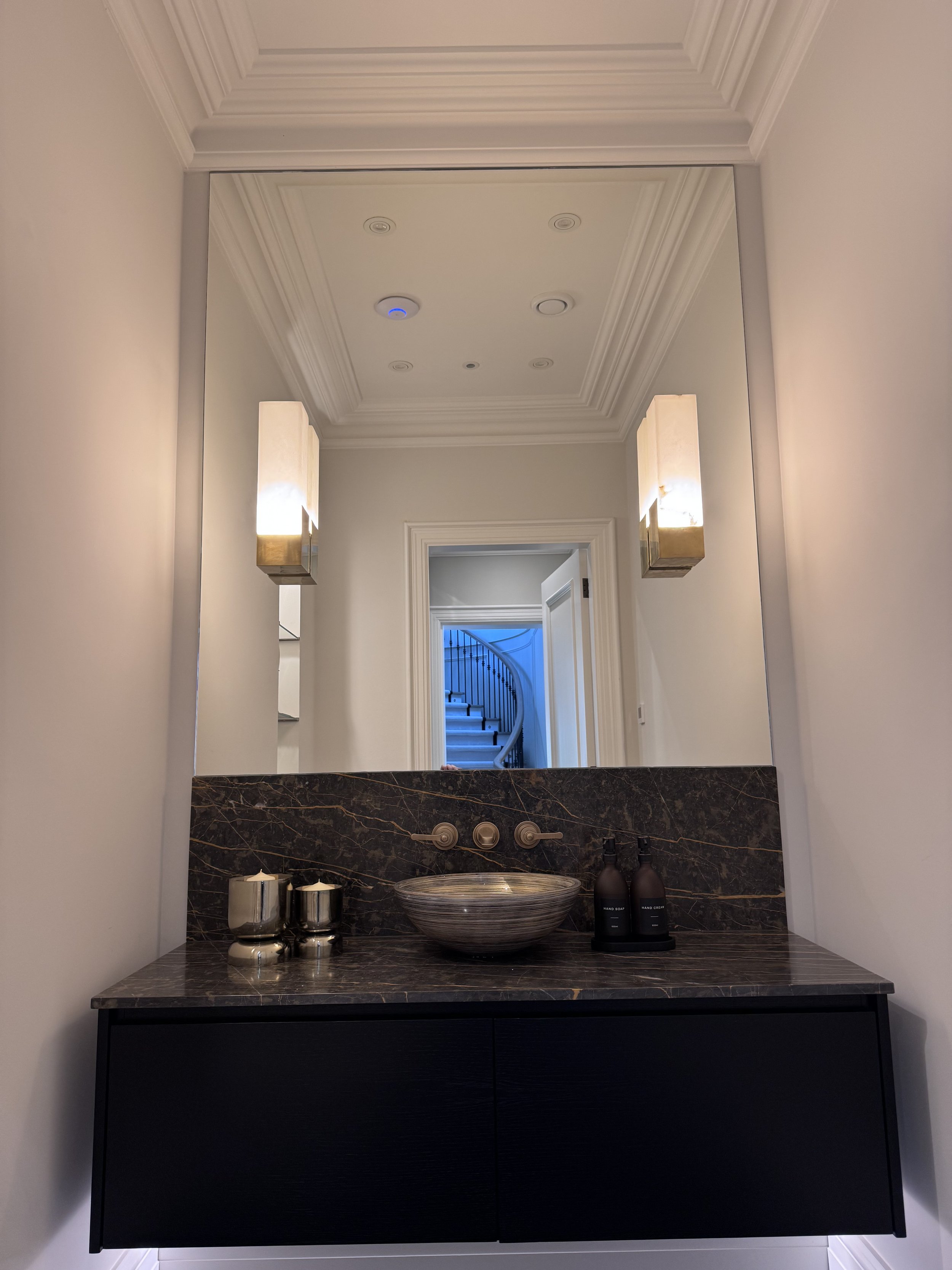 Bespoke bathroom mirror wall installed above a contemporary vanity basin with polished edges and precision fitting in a modern Surrey bathroom.
