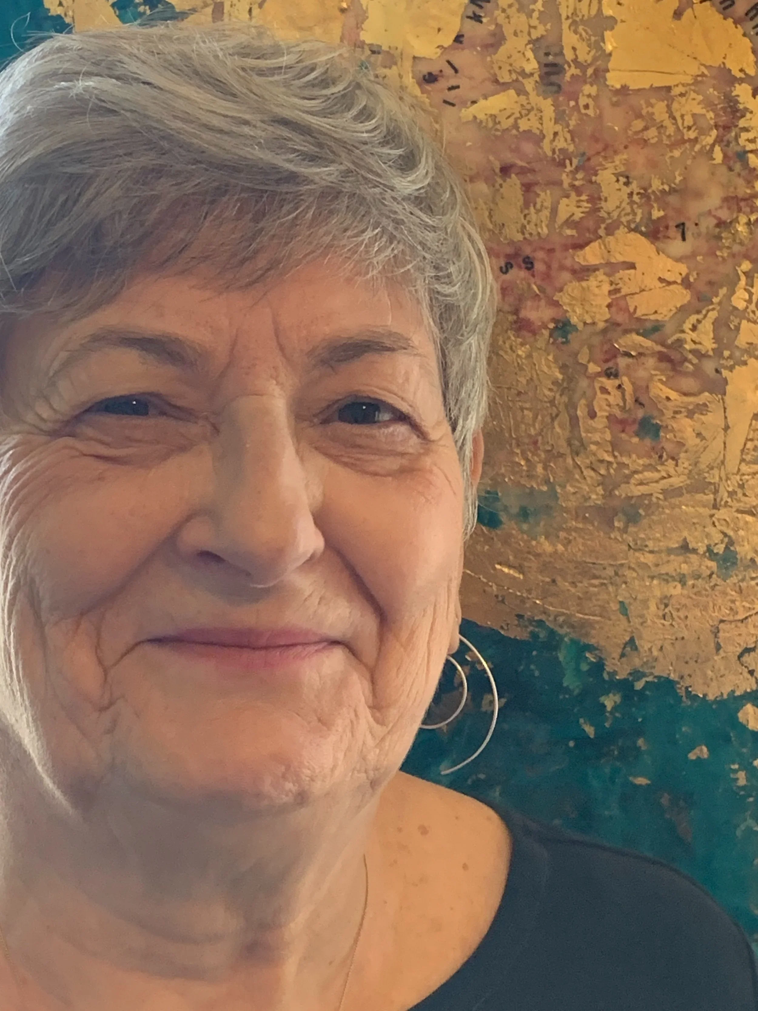 Headshot of local Guelph artist Deborah Dryden with one of her abstract paintings