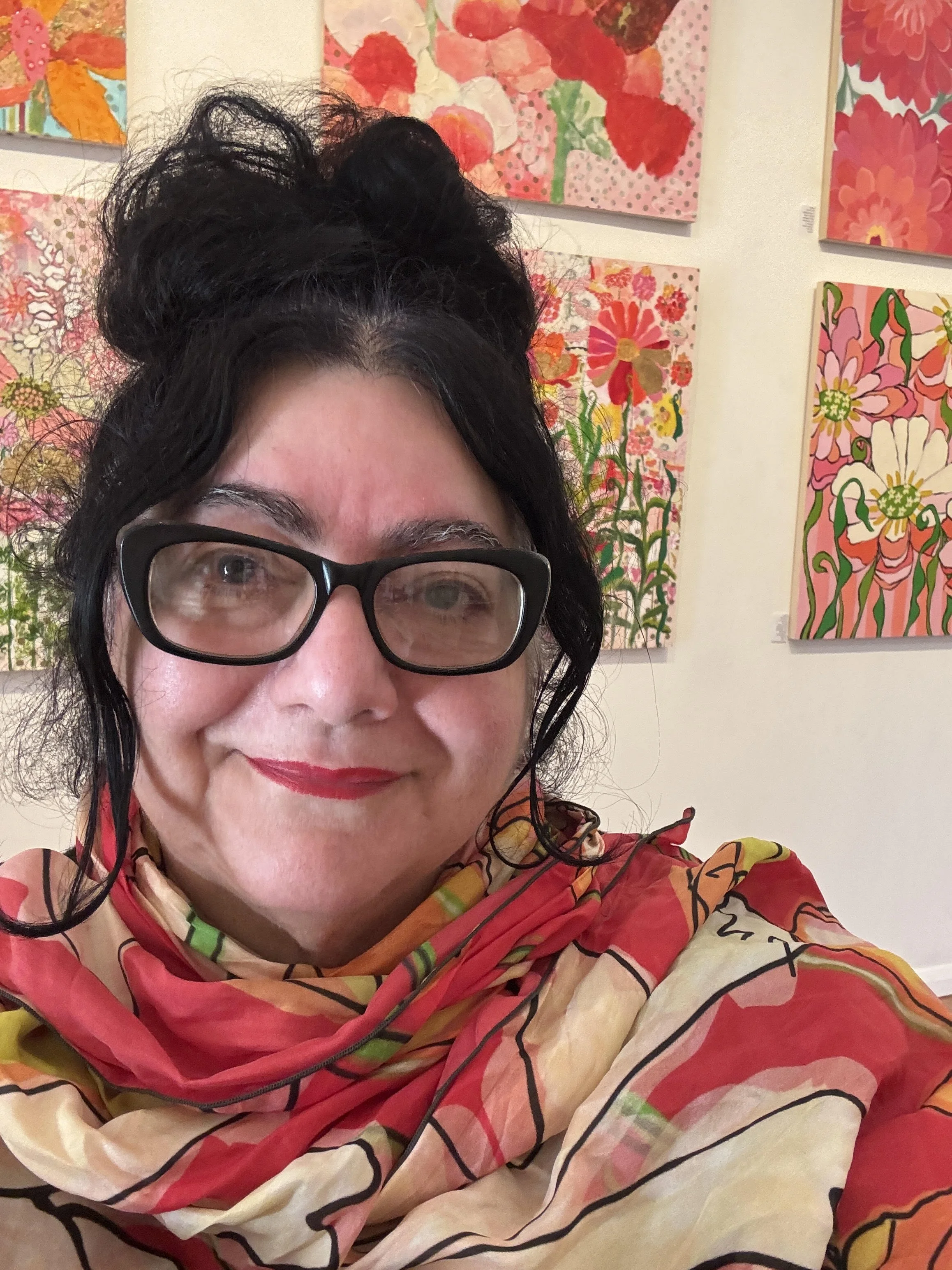 Headshot of local Guelph artist Maria Pezzano in front of her vibrant mixed media pieces