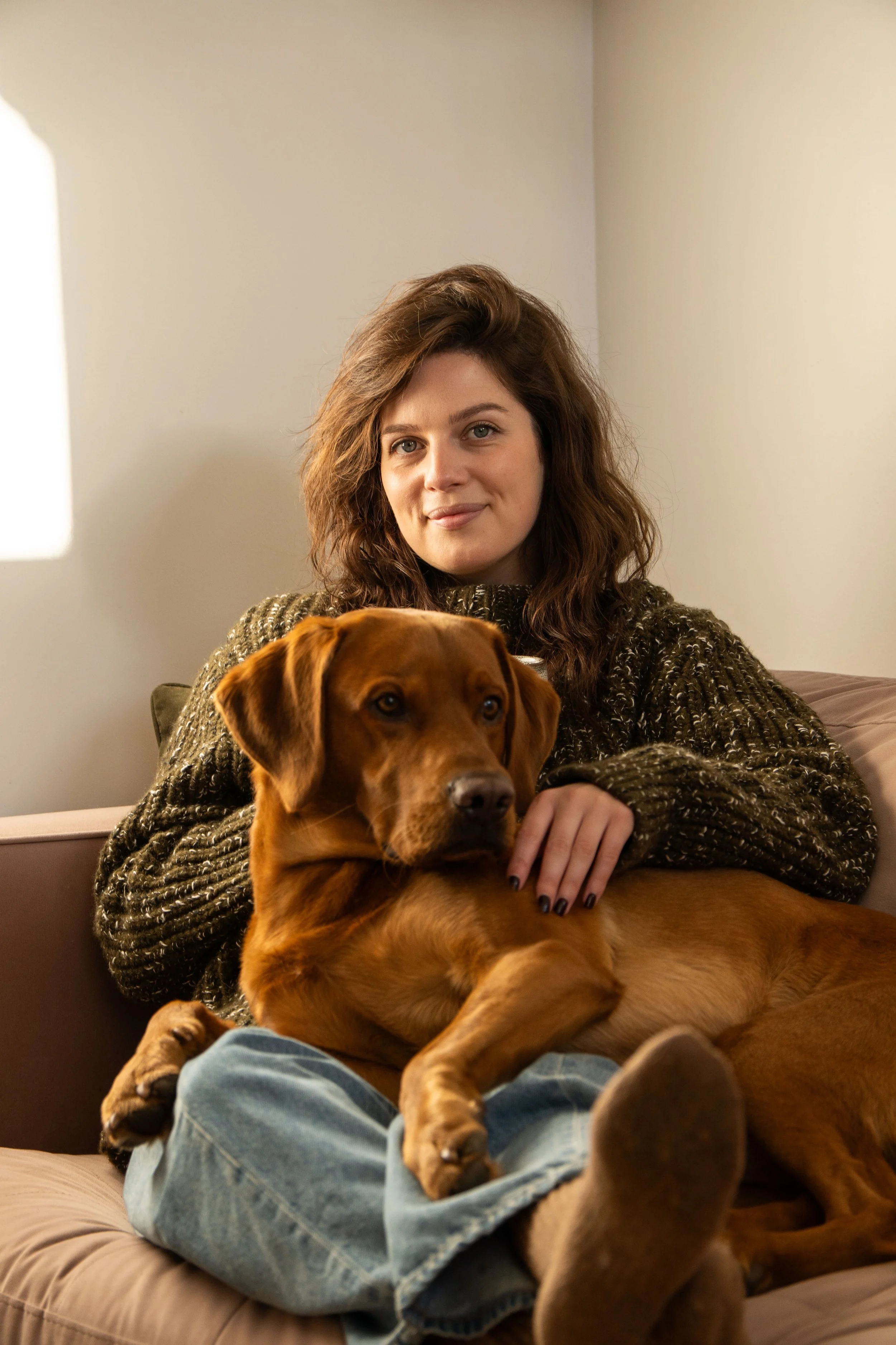 Hols, lifestyle copywriter sat on the sofa with her dog