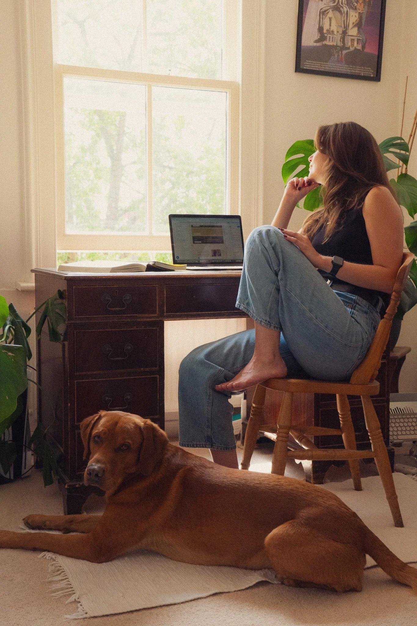 Hols from Just Custard Copy sat at a desk looking out of the window with a labrador at her feet