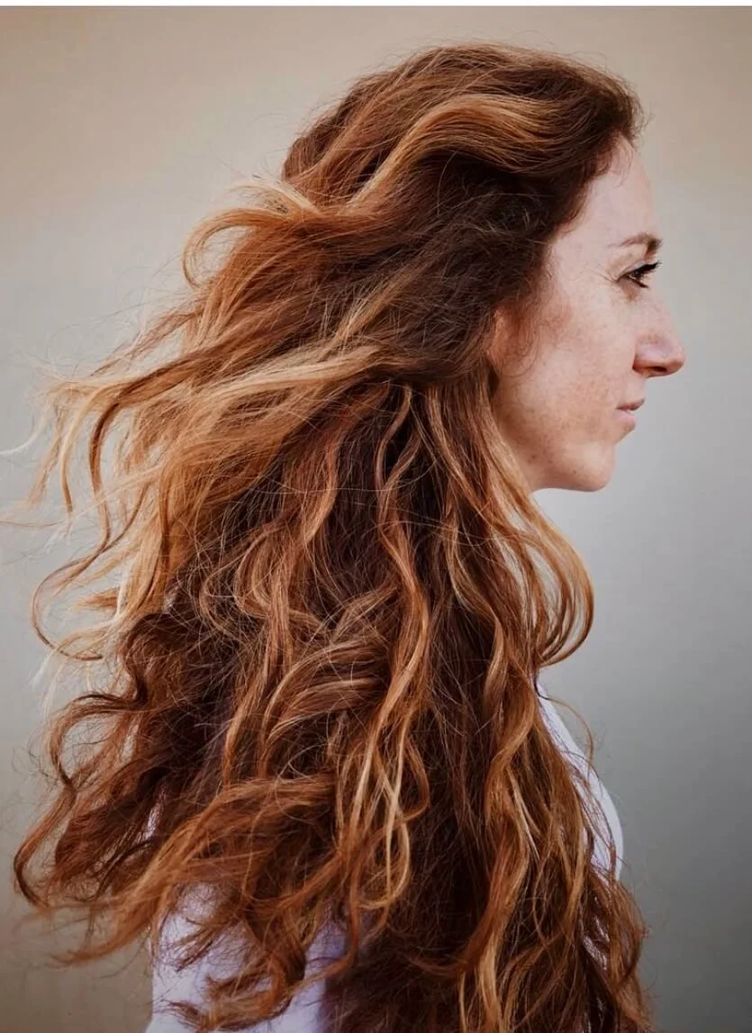 Woman with long, wavy, auburn hair in profile view