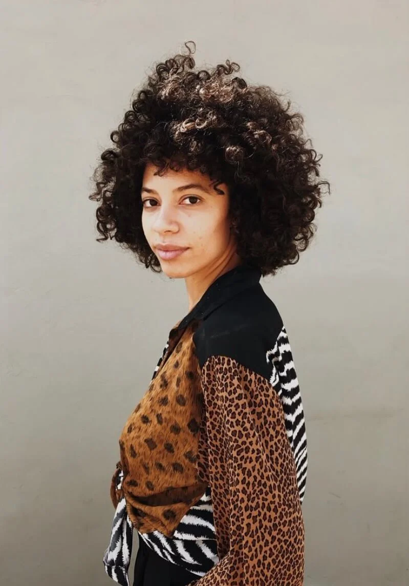 Person with curly hair wearing a patterned shirt