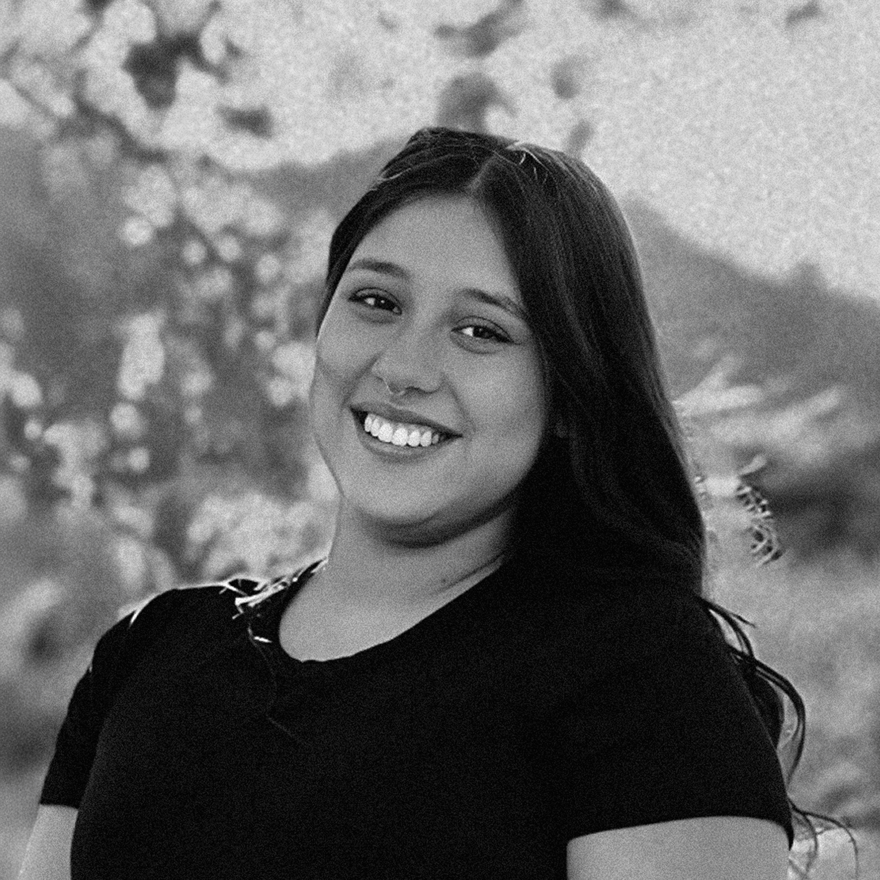 Black and white photo of a person smiling outdoors