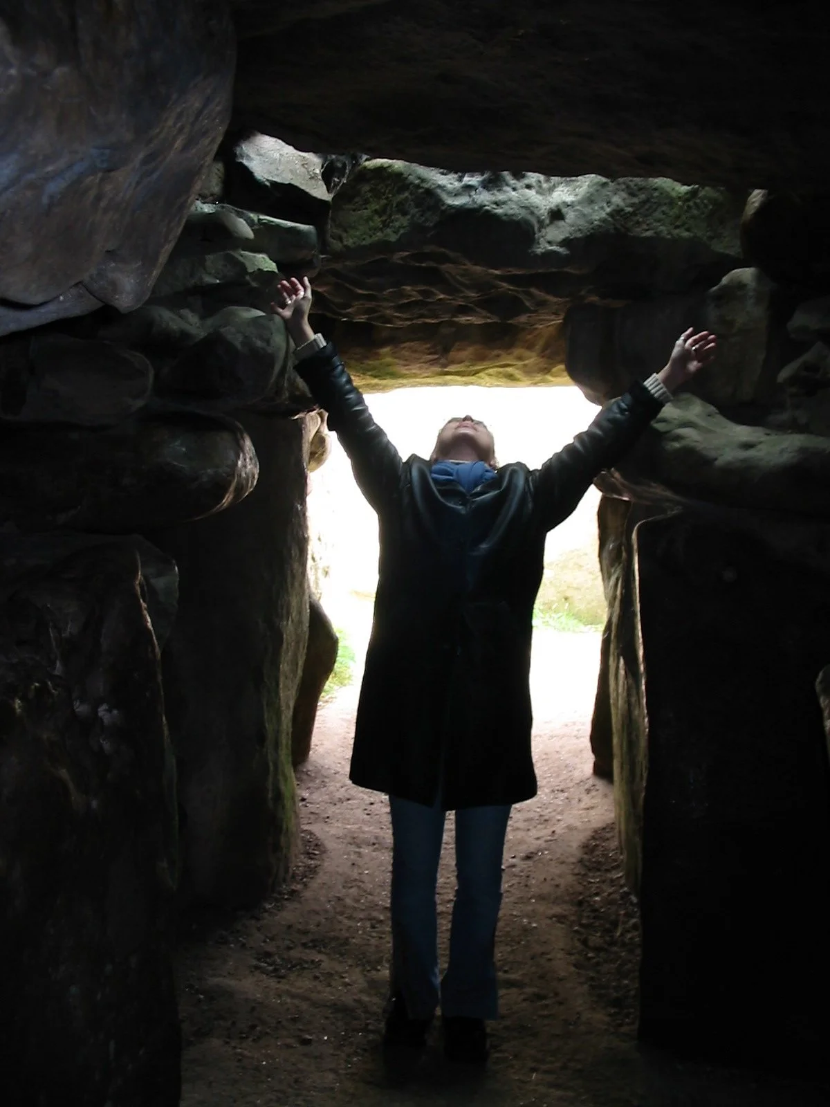 Personne levant les bras dans un passage rocheux sombre.