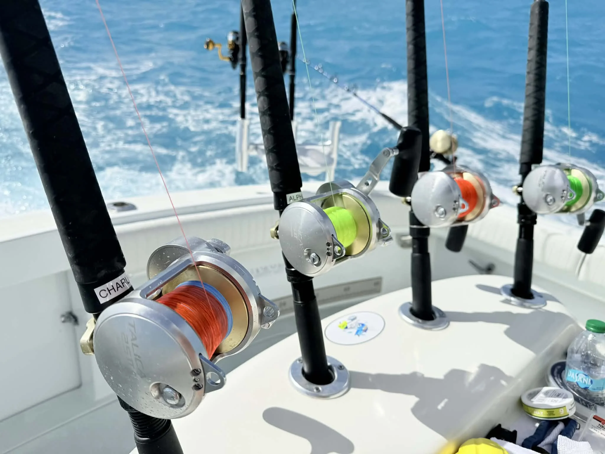 Multiple fishing rods with reels attached are mounted on a boat, with the ocean visible in the background.