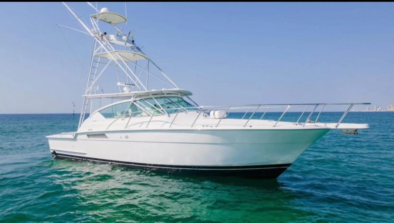 A white yacht floating on the ocean under a clear blue sky.