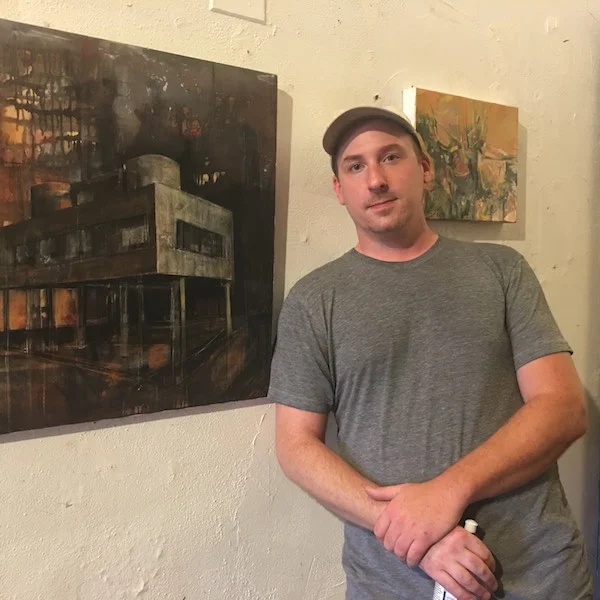 Brendan Day standing outside his studio at the Harrison Center between his oldest (left) and latest artworks.