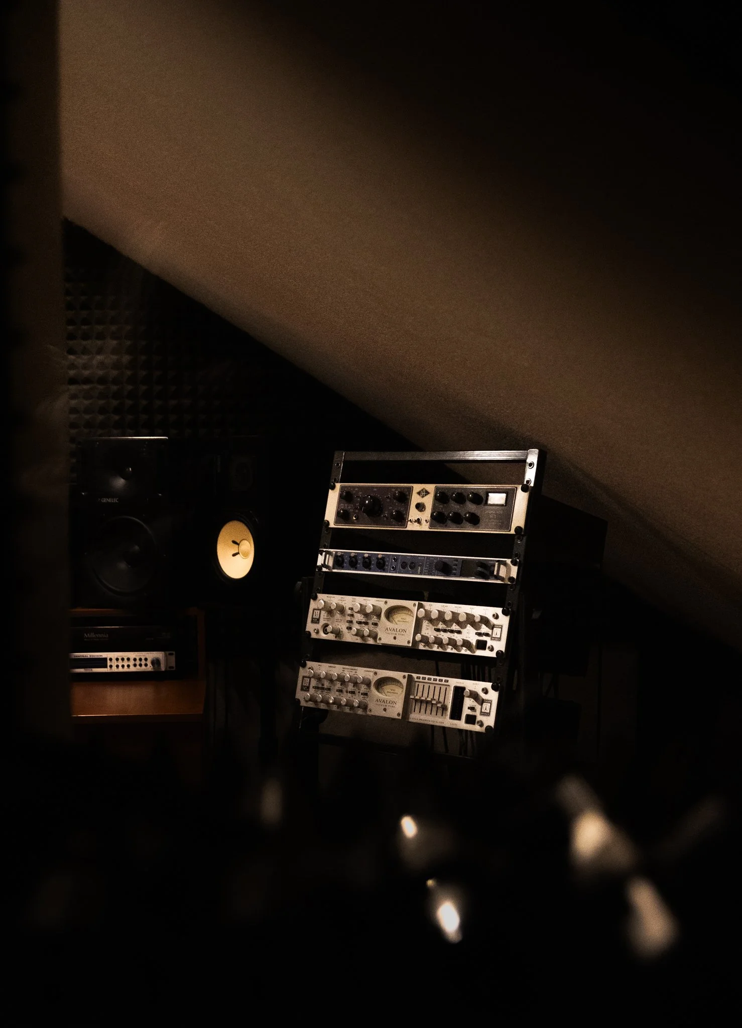 Aufnahme eines Tonstudios mit kreativen Audio-Equipment unter einer schrägen Decke, beleuchtet in warmem Licht.