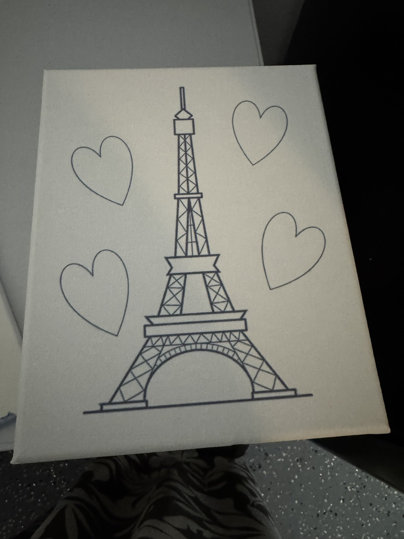 A white canvas with a black line drawing of the Eiffel Tower surrounded by four outlined hearts.