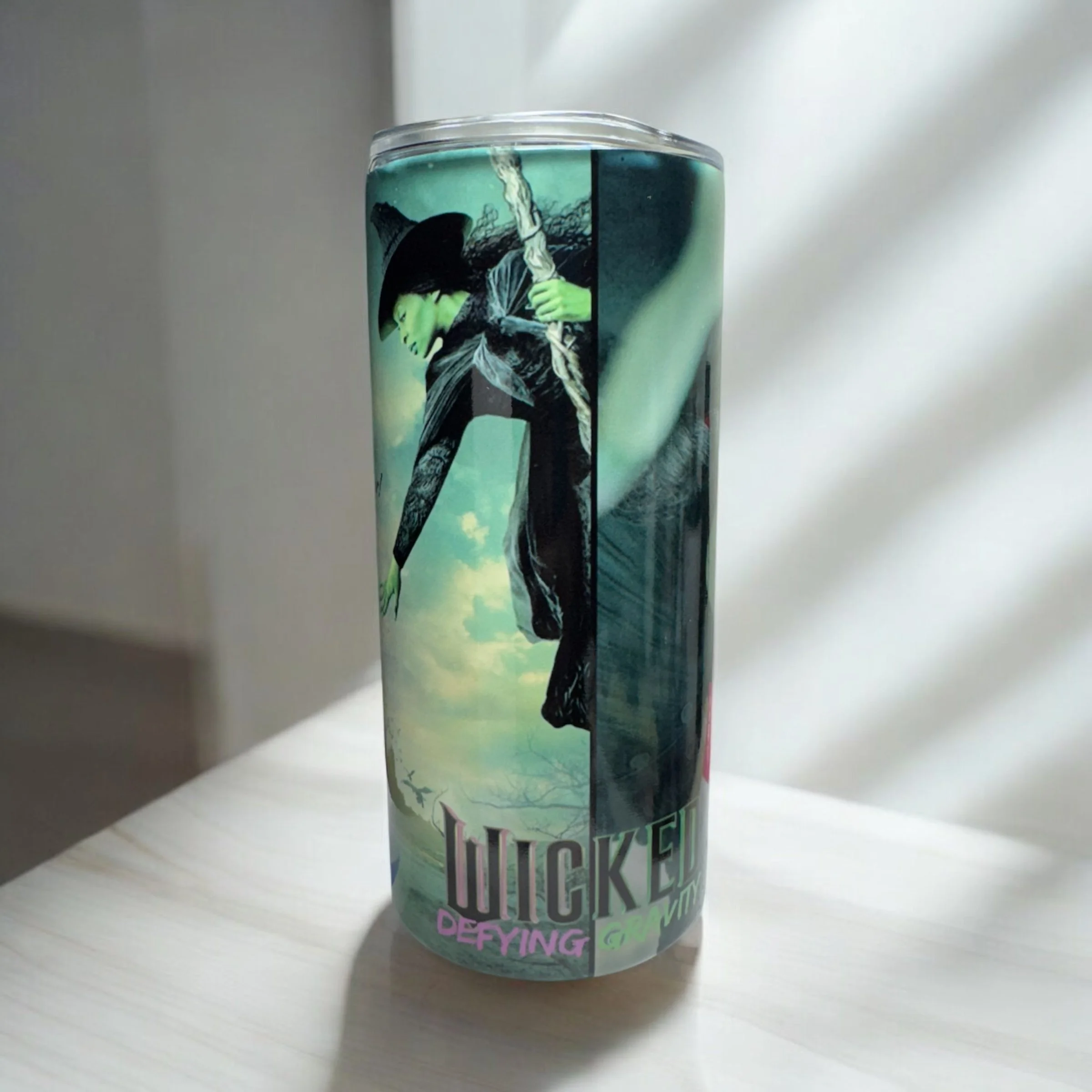 A tall, cylindrical can featuring a Witchy-themed design with a green-skinned witch holding a broom, set against a cloudy sky background.