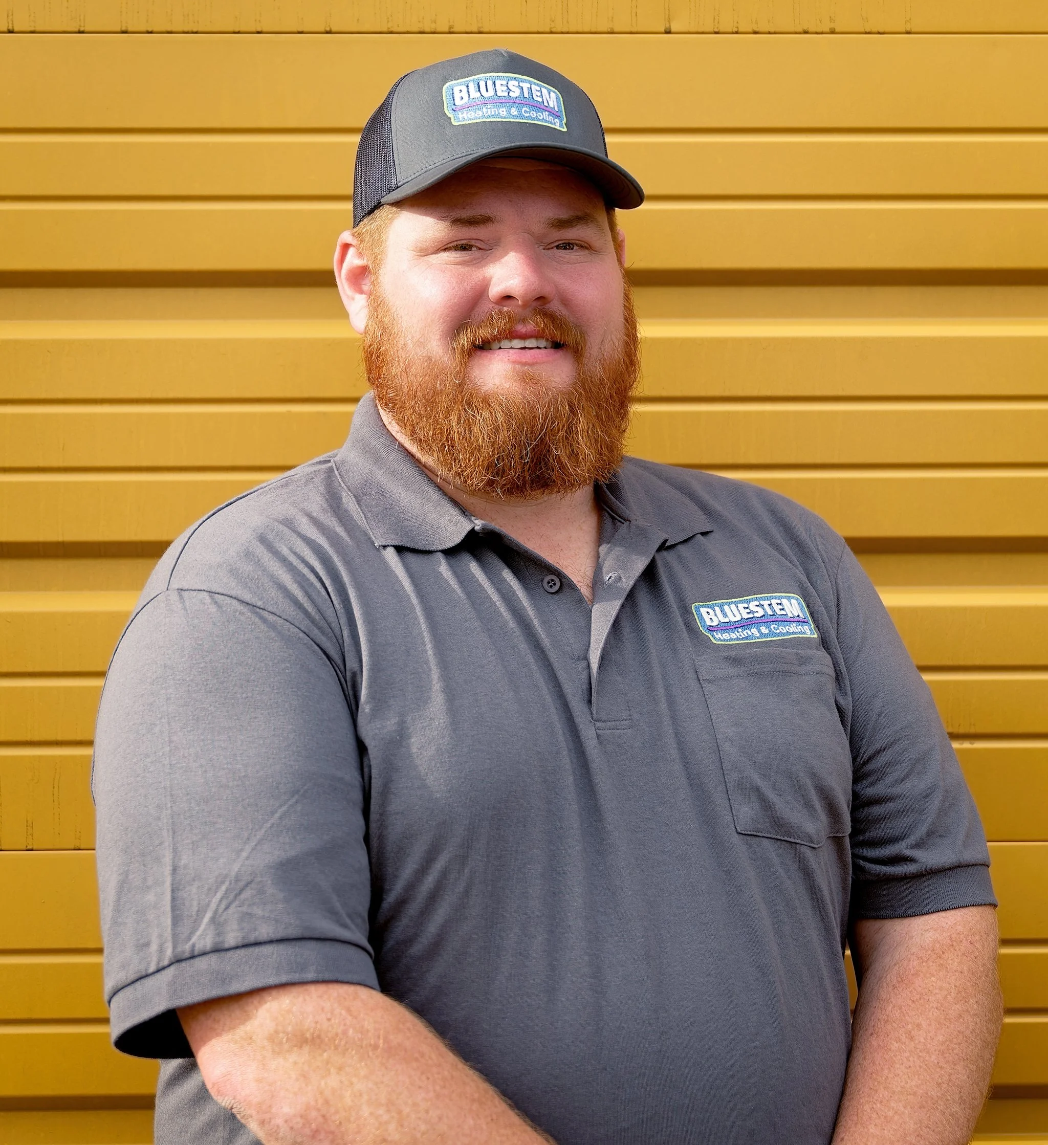 A smiling Bluestem HVAC service technician on a yellow background