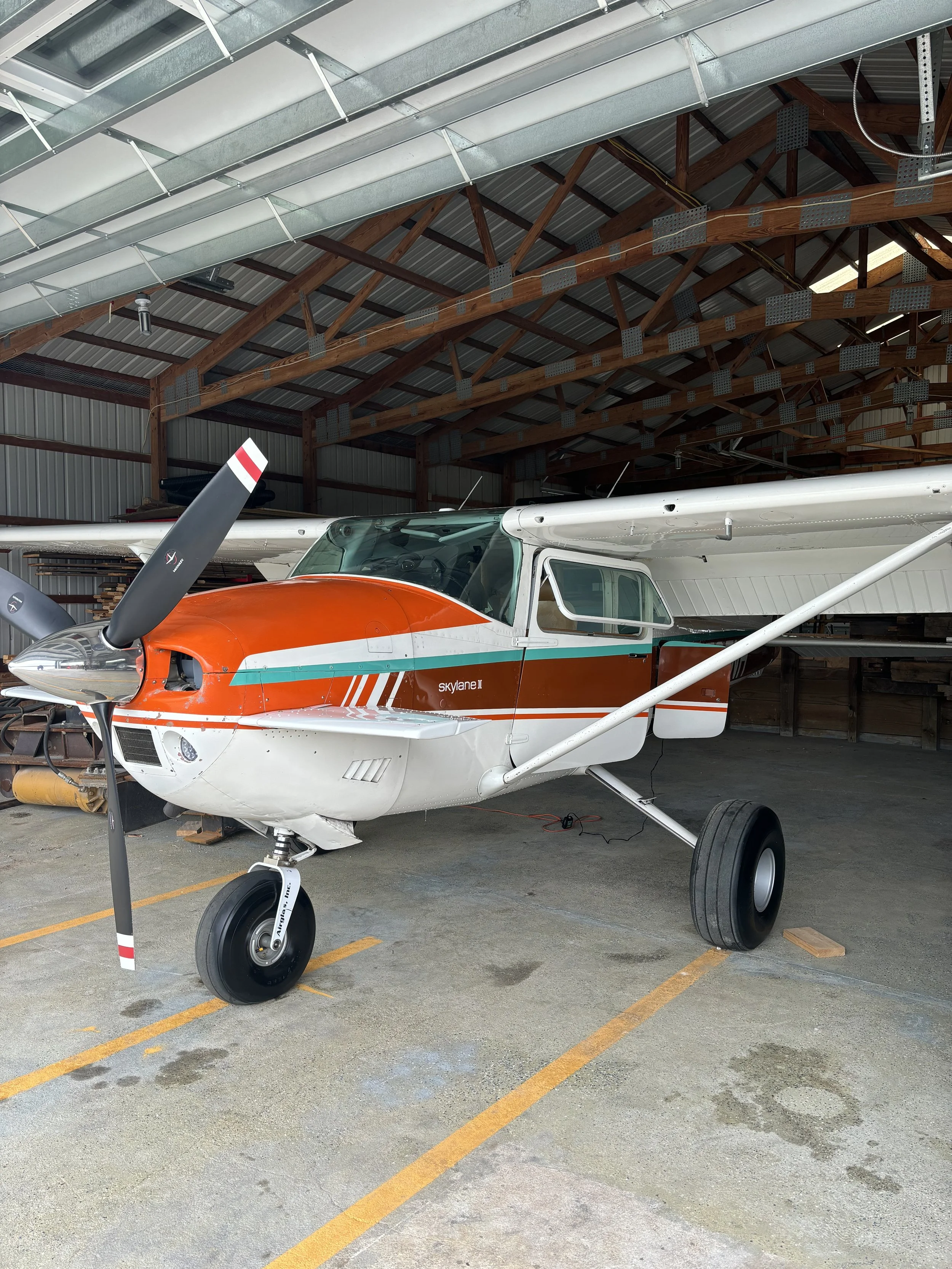 Scenic view of a large lake with turquoise waters, surrounded by rolling green hills and rugged mountains under a cloudy sky.