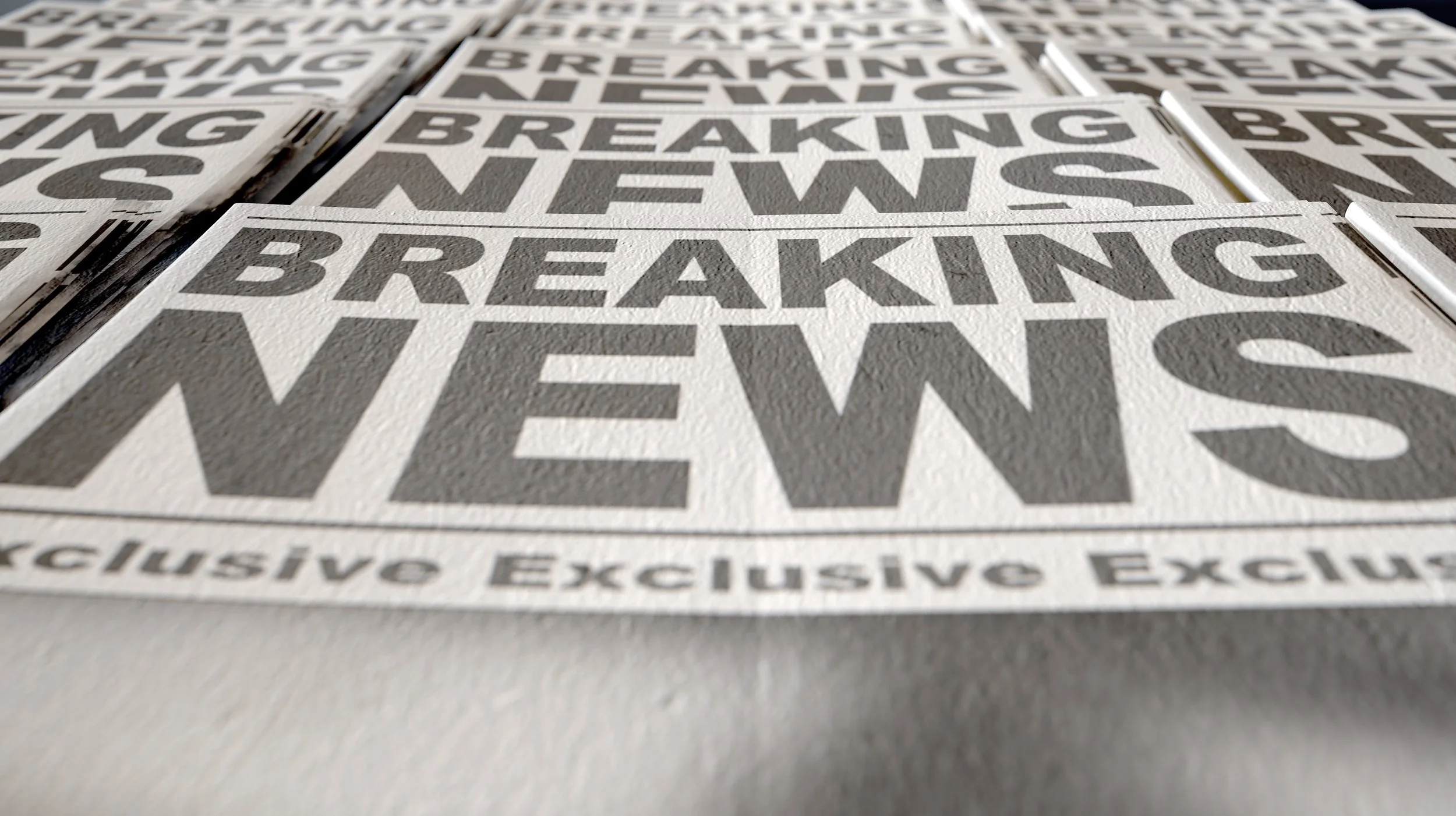 Multiple signs with the words "Breaking News" in black text on a white background.