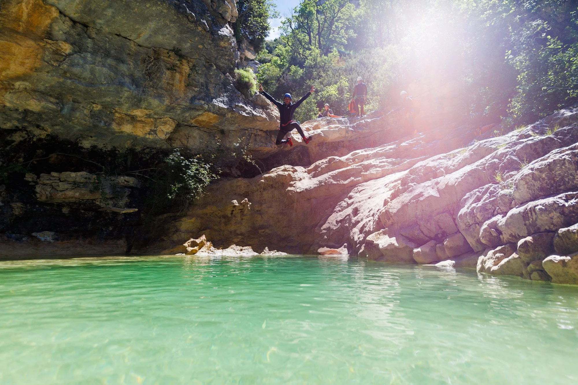Un adulte saute de 3 mètres dans une piscine naturelle à l'eau transparente dans un canyon dans les Gorges du Verdon