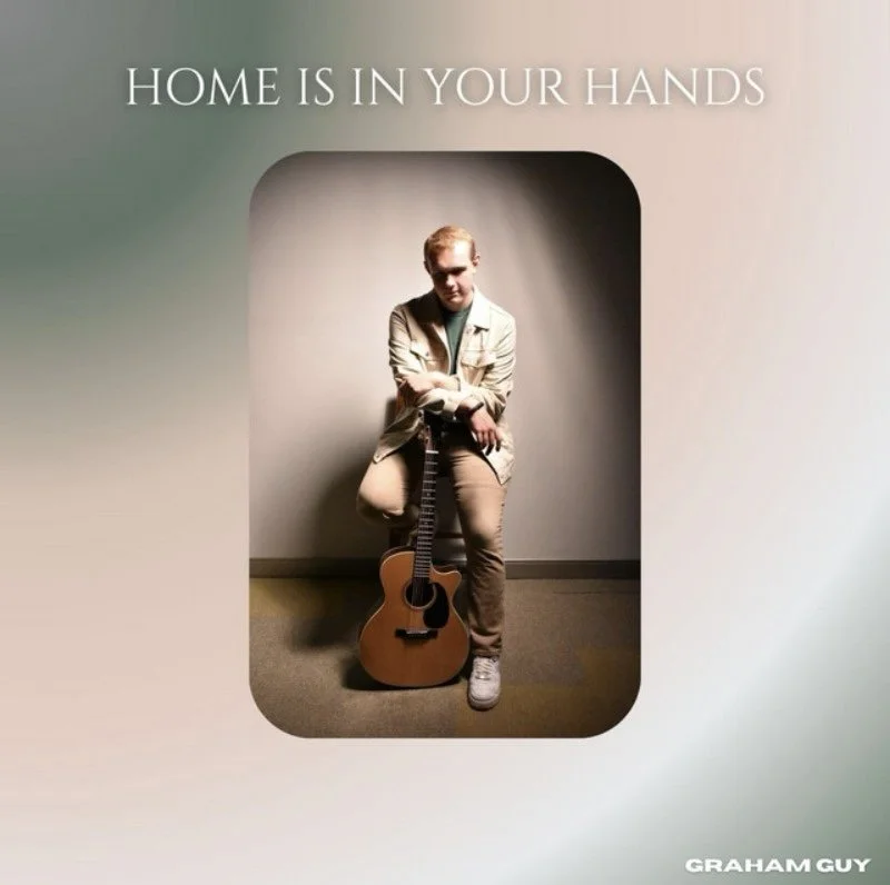A person sitting on a chair with a guitar at their feet, in front of a plain background, with the text 'Home is in your hands' above.