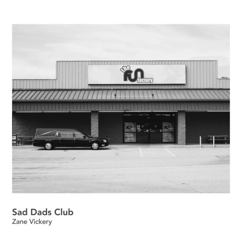 Front view of a store called 'The FQ Factory' with a parked van in the parking lot.