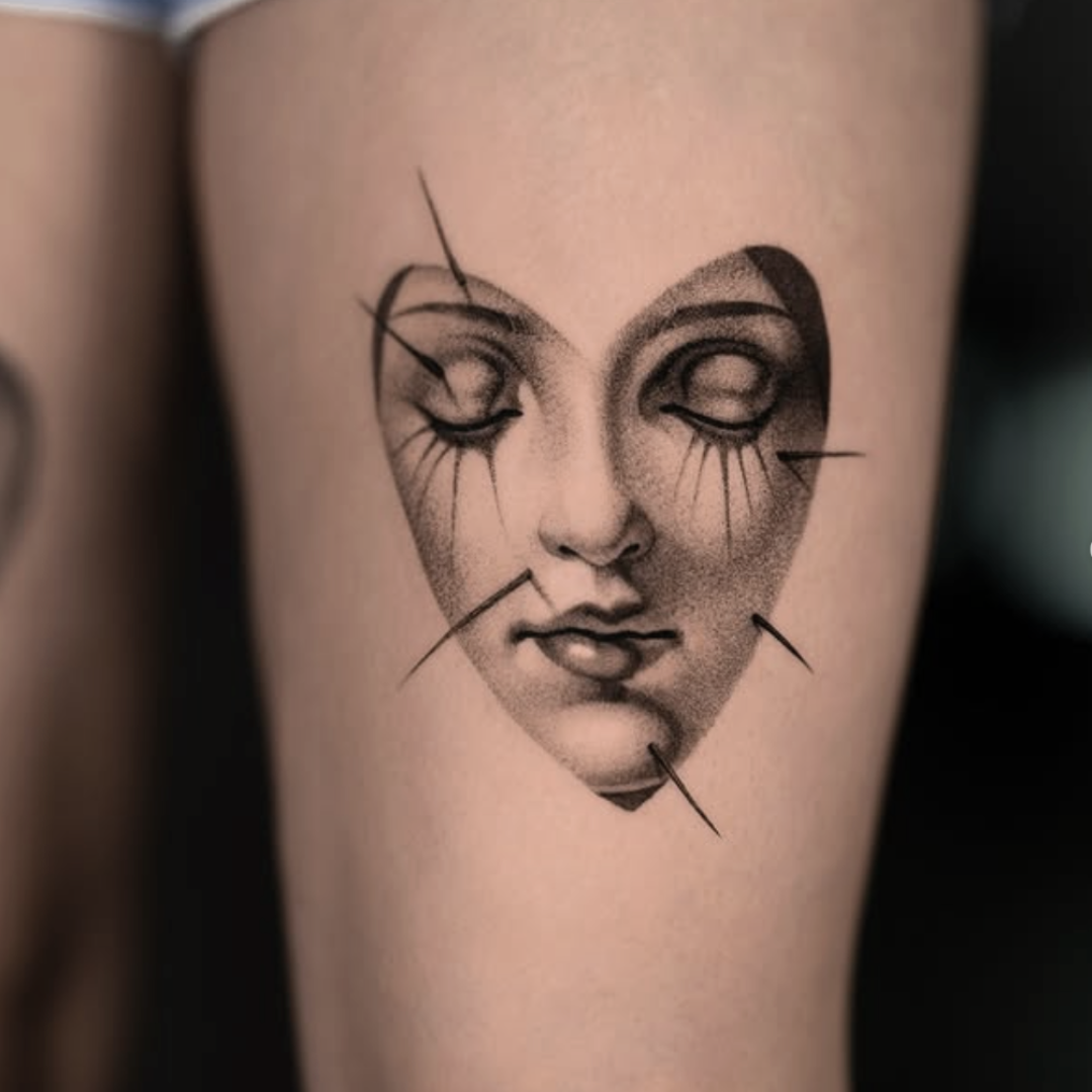 Realistic cracked porcelain face tattoo in heart shape by Brian Parrillo in Durham