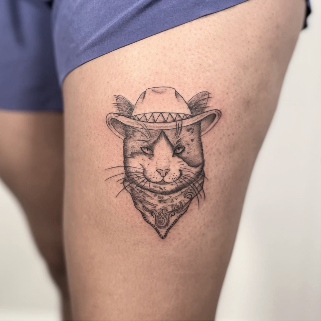 Illustrative cowboy cat tattoo with bandana by Yasmin, fine line work in Durham